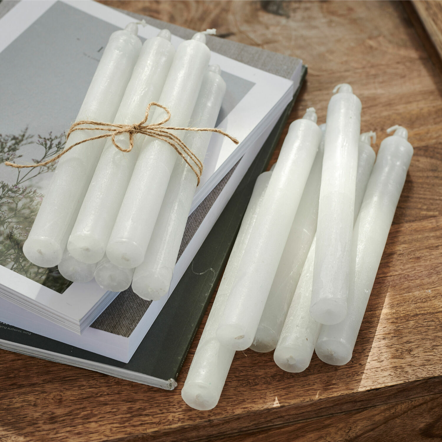 Set di 12 candele Bauceau Set di candele bianche in cera su tavolo in legno con libri, decorazione d'interni