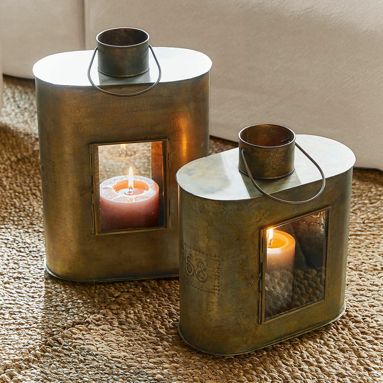 Coppia di lanterne Gemaingoutte Lanterna in metallo color ottone con manico e candela accesa su tappeto di juta