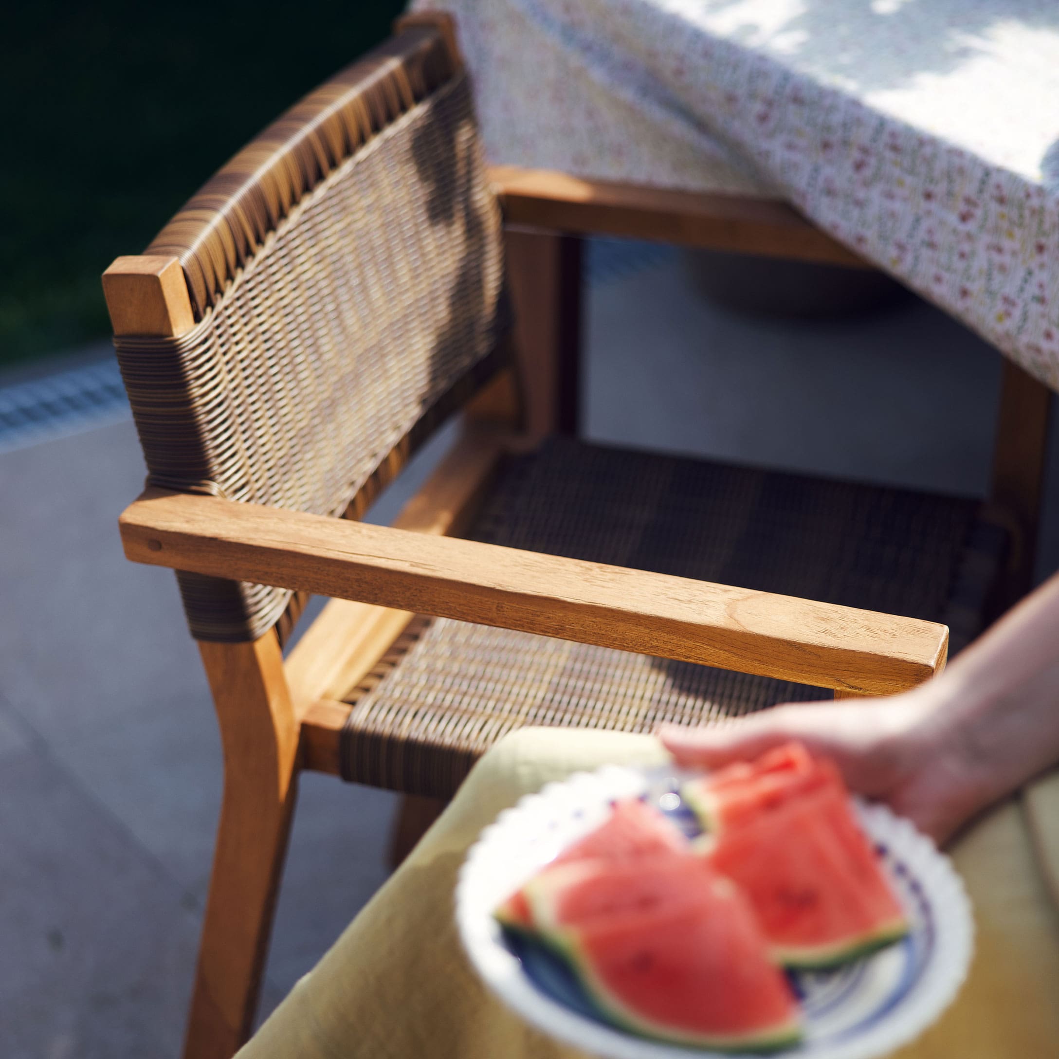 Sedia da giardino in legno e vimini naturale accanto a un tavolo con tovaglia