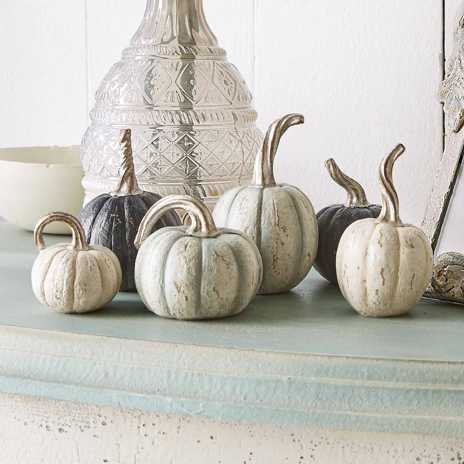 Zucca decorativa in metallo bianco e nero su mensola chiara per decorazione autunnale