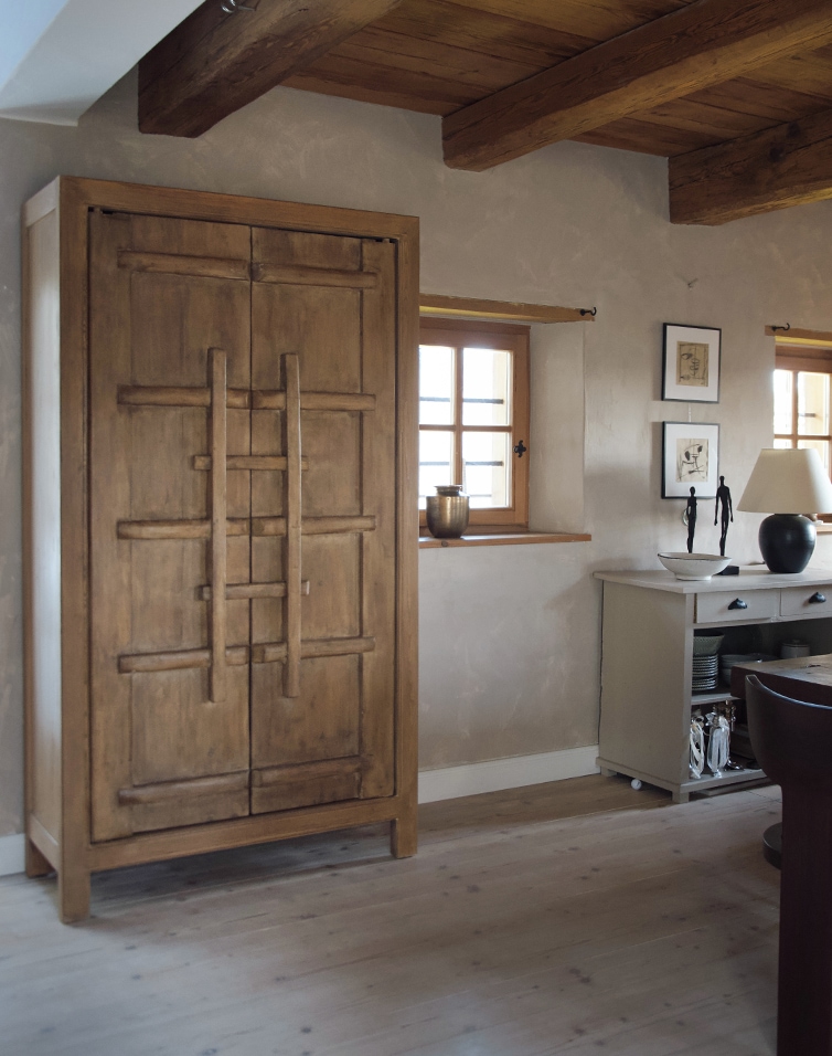 Armadio in legno colore naturale in stanza luminosa con decorazioni e finestre in legno
