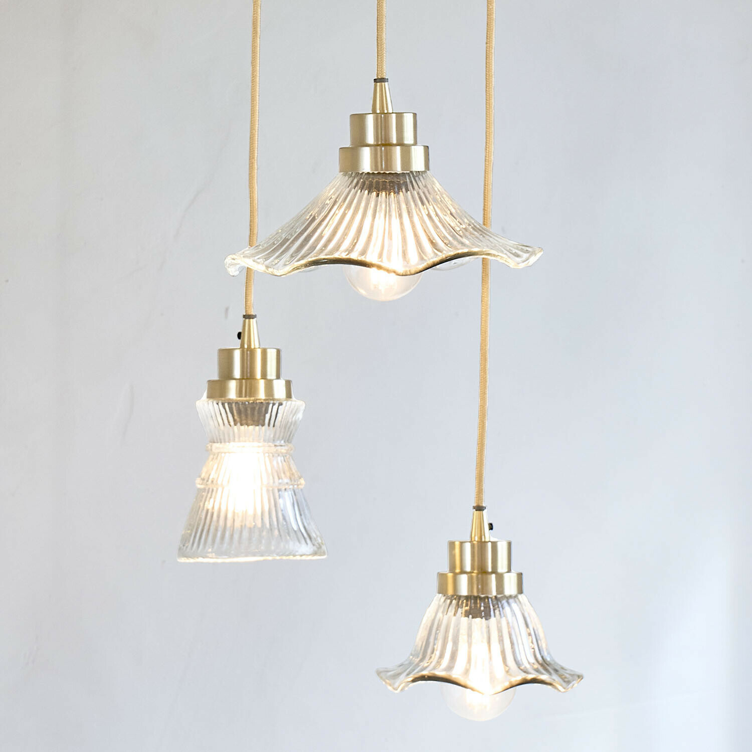 Set di 3 lampade a sospensione Lunaras Set di tre lampade a sospensione in vetro con dettagli in ottone e cavo giallo per illuminazione interna