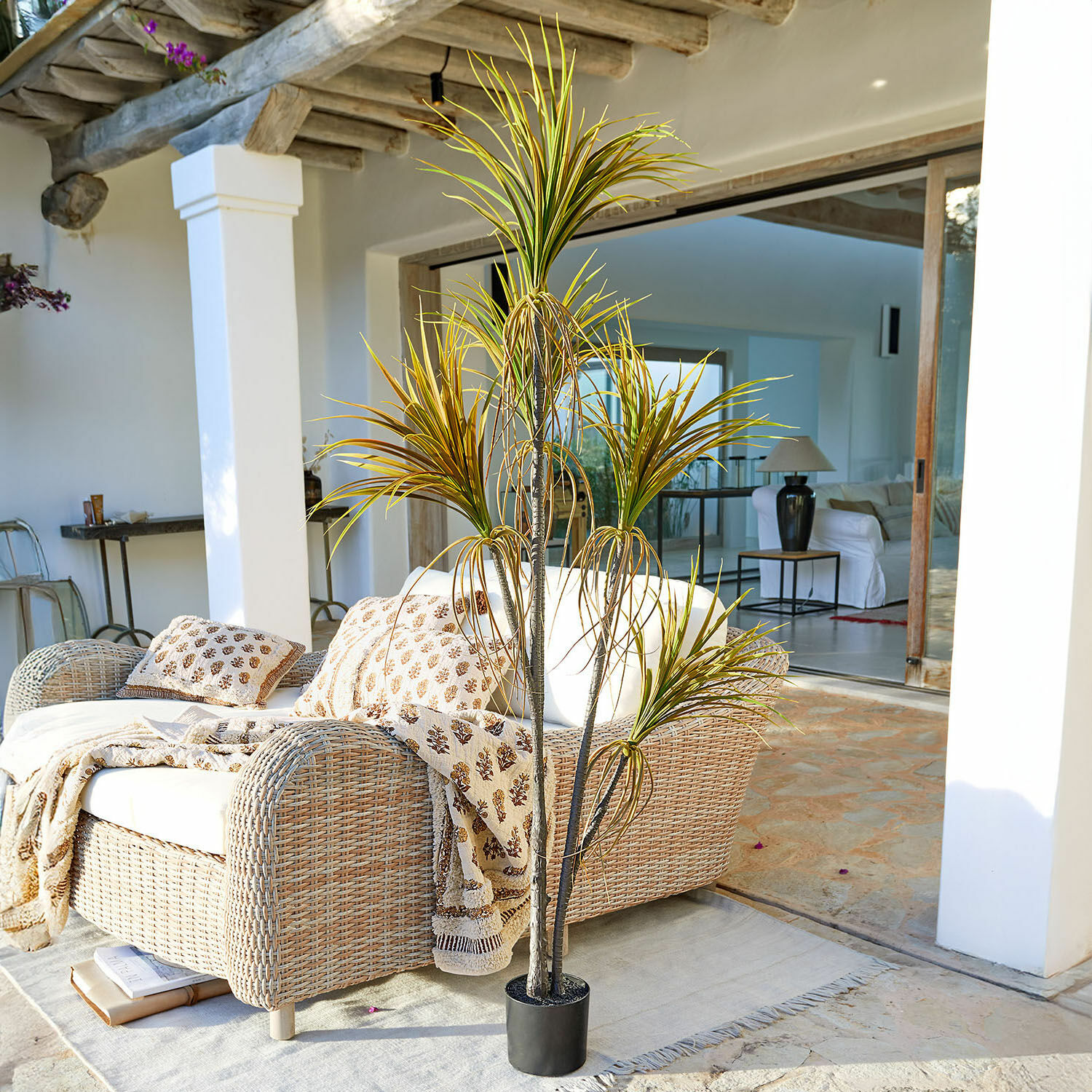 Pianta decorativa in vaso Ancerac Pianta artificiale in vaso nero su terrazza con divano in rattan e coperta chiara