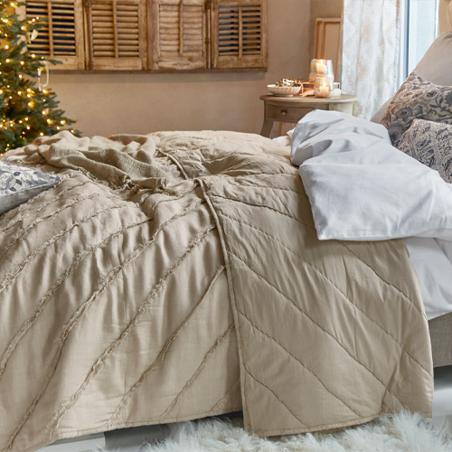 Coperta beige in tessuto morbido su letto in camera accogliente con decorazioni natalizie