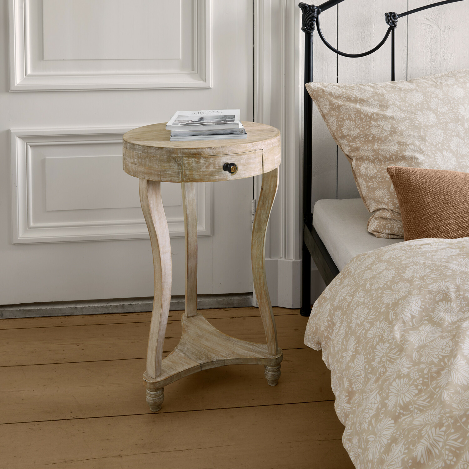 Tavolino di complemento Elmbury Tavolino rotondo in legno chiaro con cassetto accanto a letto con biancheria da letto beige a fiori