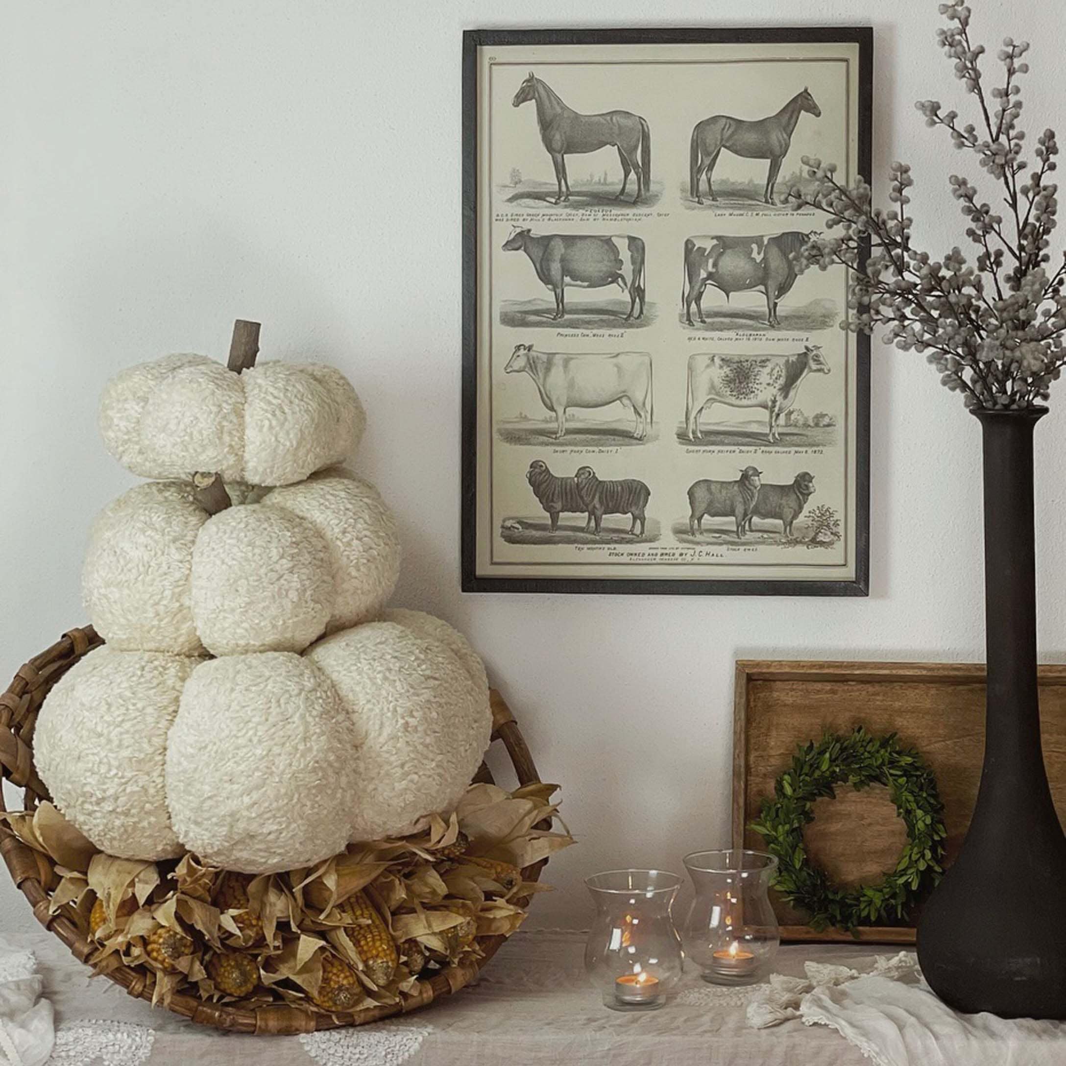 Decorazione autunnale con zucca bianca in peluche in cesta di vimini e candele sul tavolo
