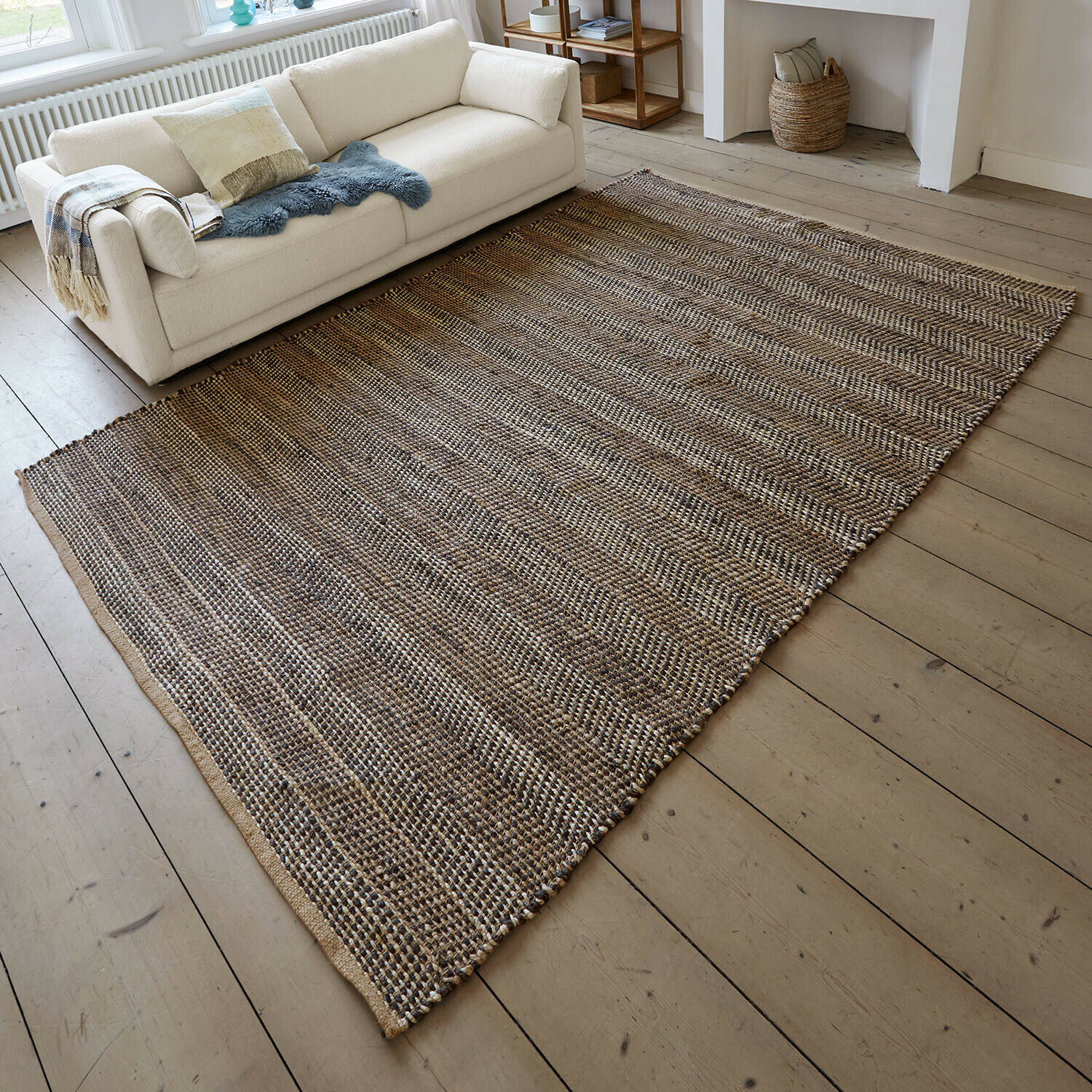 Tappeto Myråsen Tappeto in fibra naturale marrone e beige su pavimento in legno chiaro accanto a divano bianco
