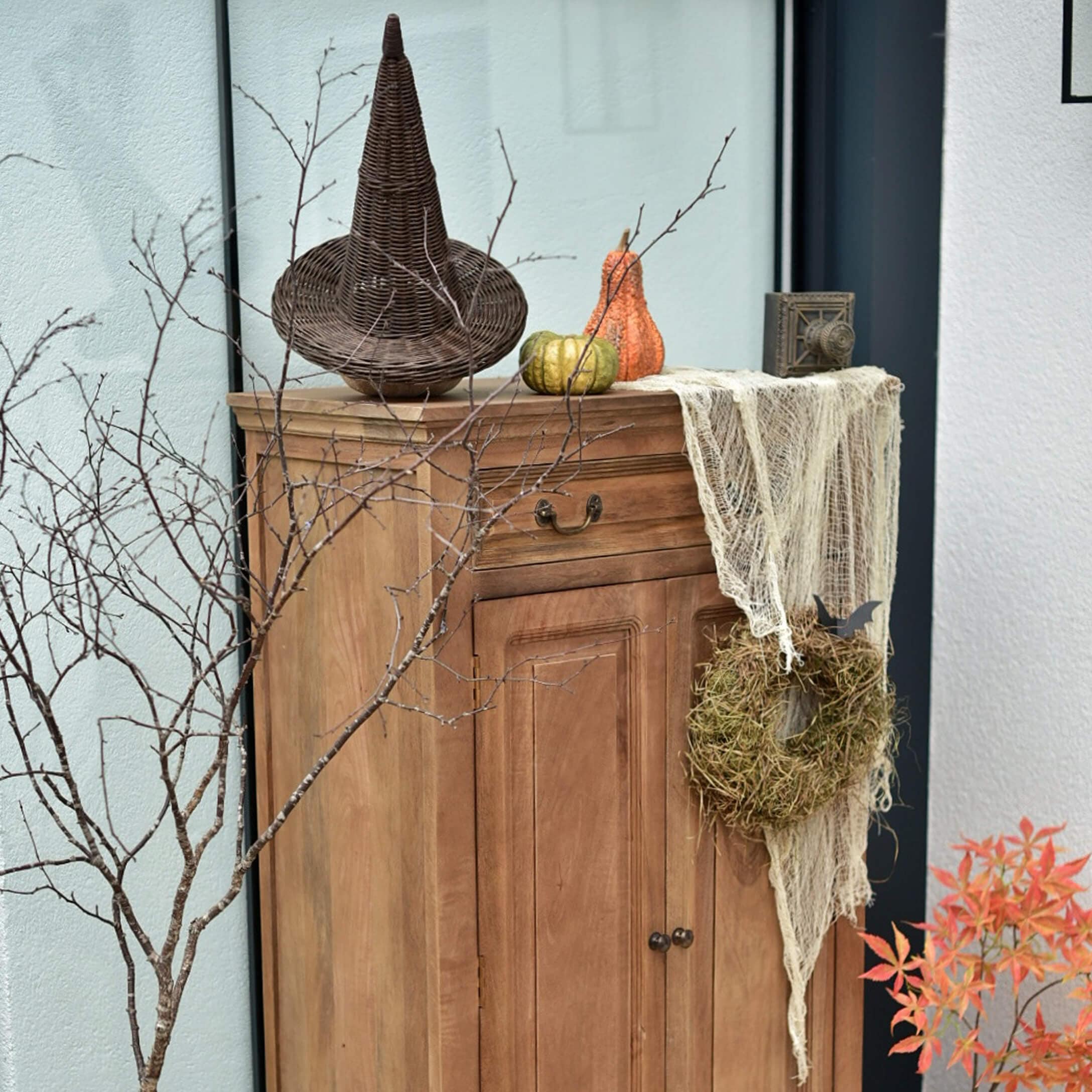 Mobile in legno con decorazioni autunnali: cappello di vimini, zucche e corona di muschio