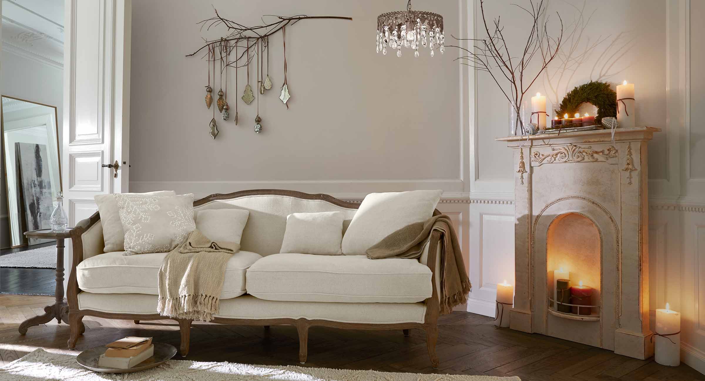 Divano beige con struttura in legno in soggiorno classico con camino e decorazioni a parete