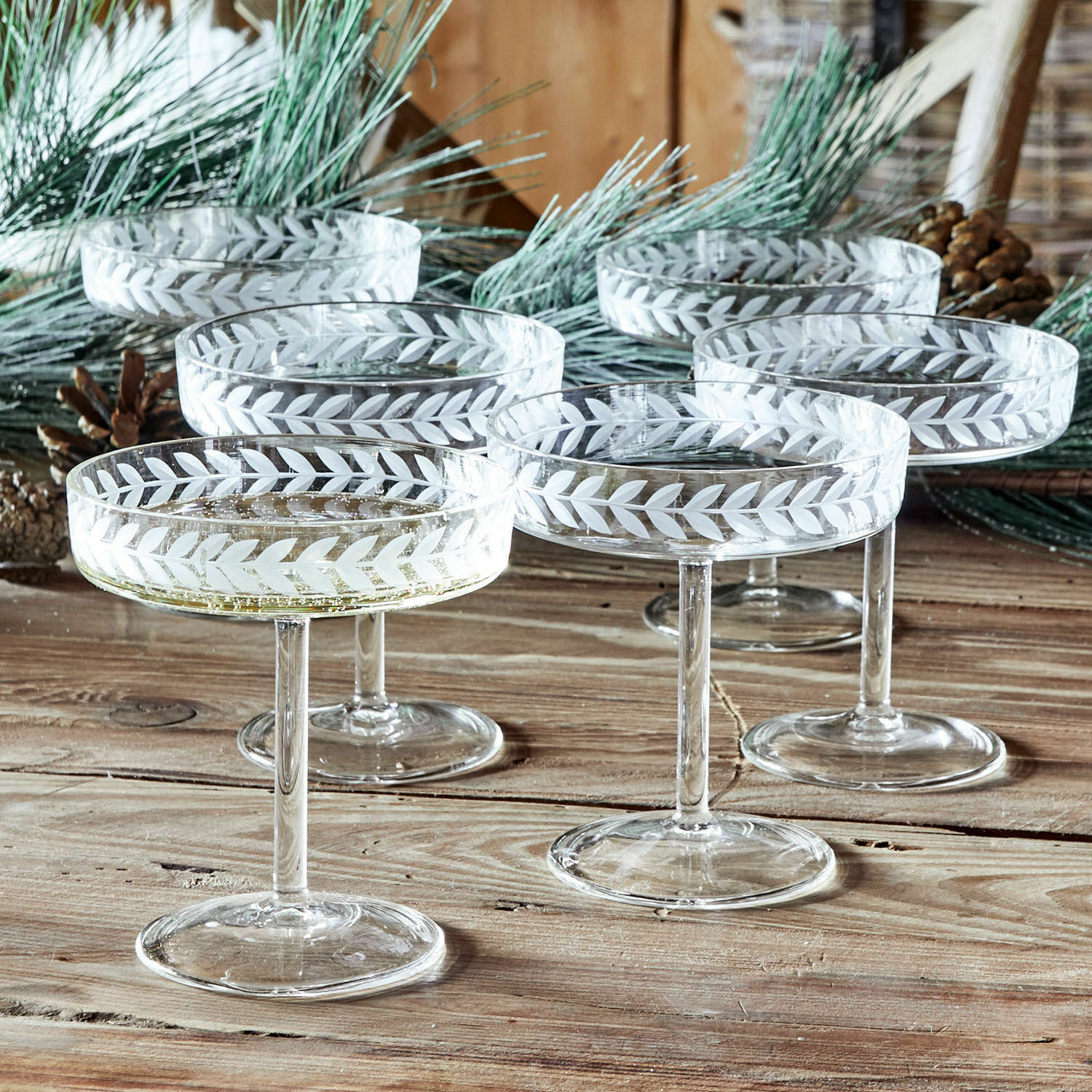 Set di 6 coppe per champagne Macomb Set di sei calici da champagne in vetro con motivo inciso a foglie su tavolo in legno rustico