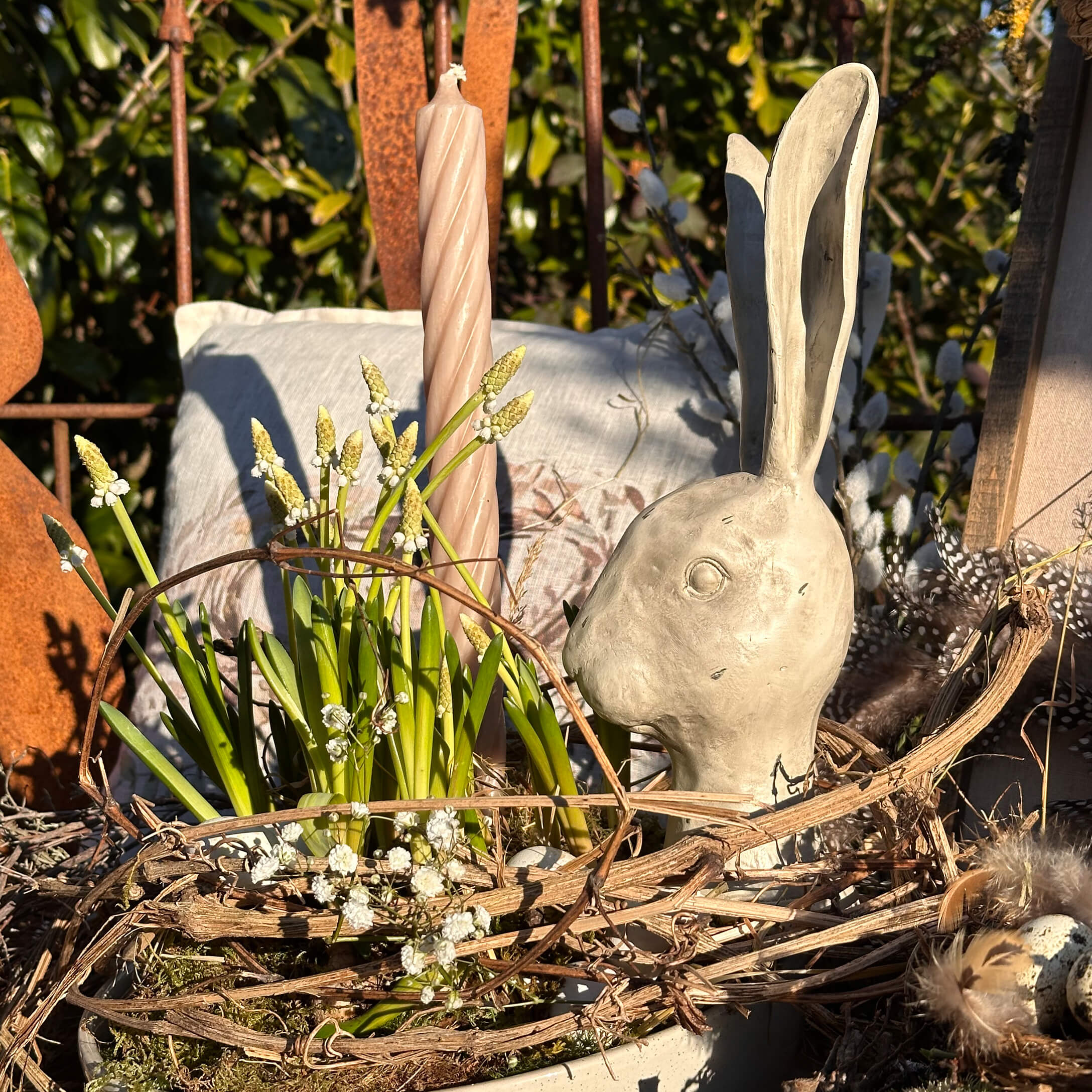 Decorazione pasquale con testa di coniglio in ceramica grigia e fiori verdi in cesta naturale