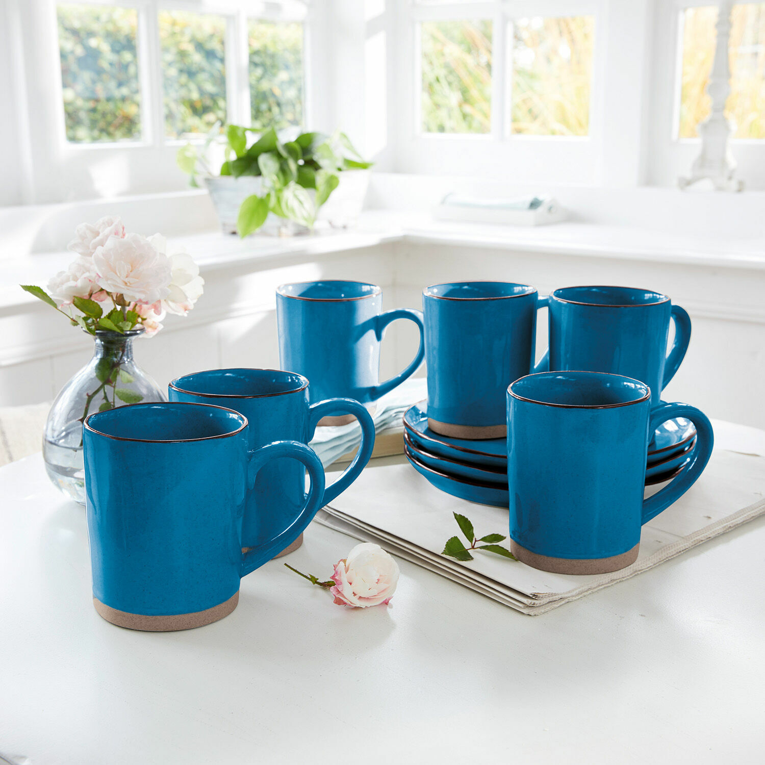 Set di 6 tazze Biarré Set di sei tazze in ceramica blu con base marrone su tavolo bianco in cucina luminosa