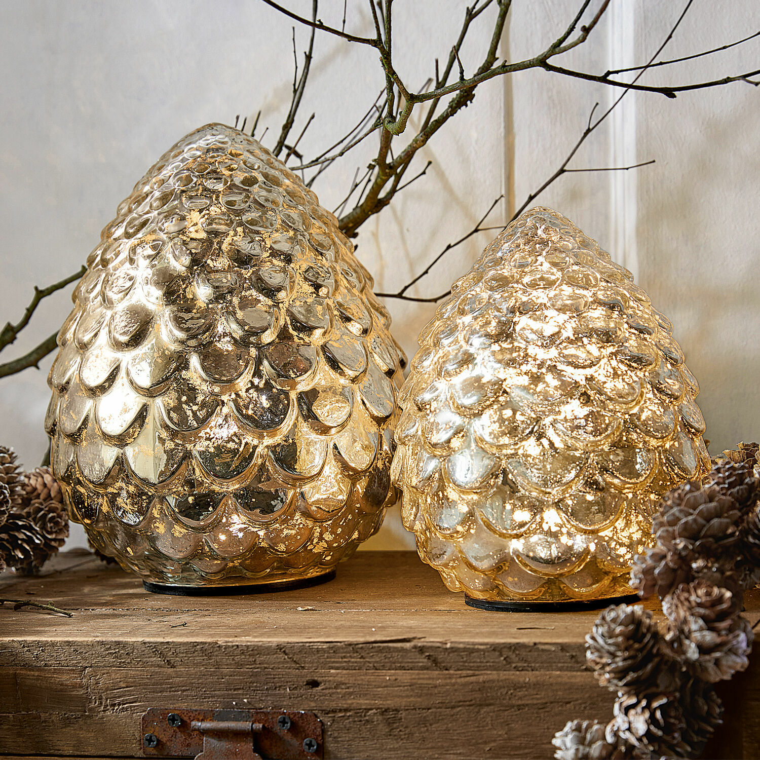 Coppia di pigne decorative Ibaque Due coni decorativi in vetro dorato con texture a scaglie su piano in legno con pigne