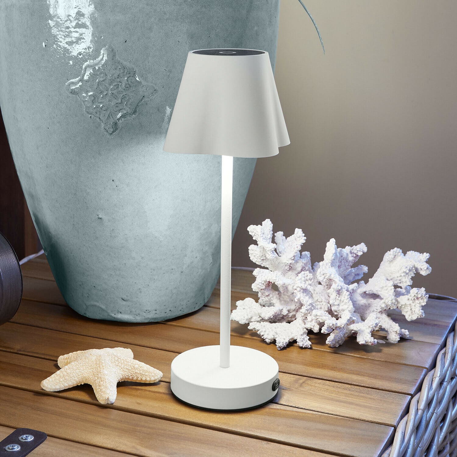 Lampada da tavolo bianca in metallo con paralume su tavolo in legno con decorazioni marine