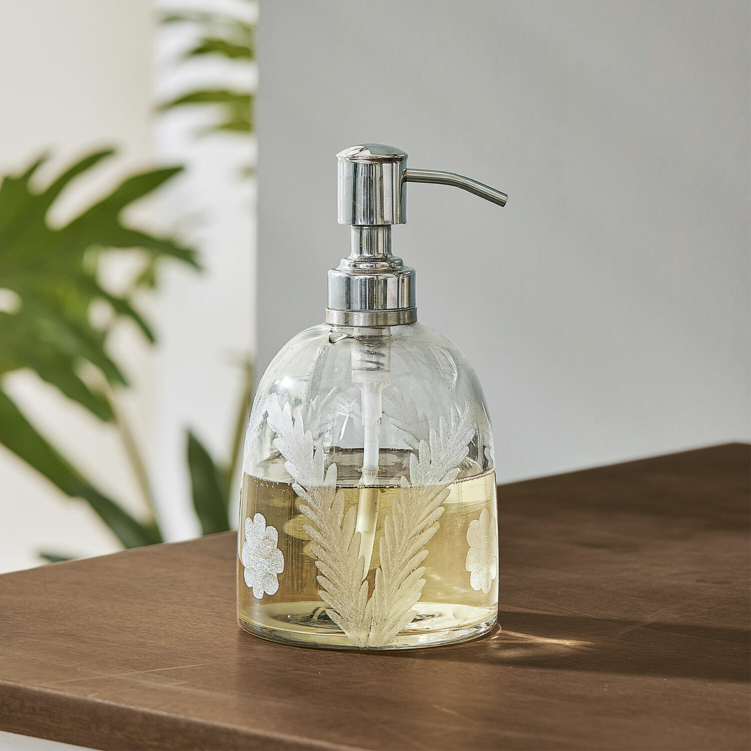 Dispenser per sapone Crystal Dispenser per sapone in vetro con pompa metallica e motivo di foglie bianche su tavolo marrone