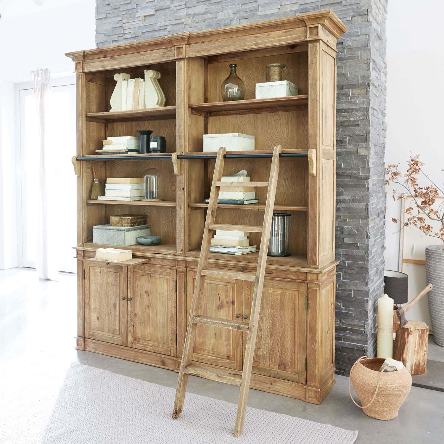 Grande libreria in legno con scala e scaffali pieni di libri e decorazioni in interno luminoso