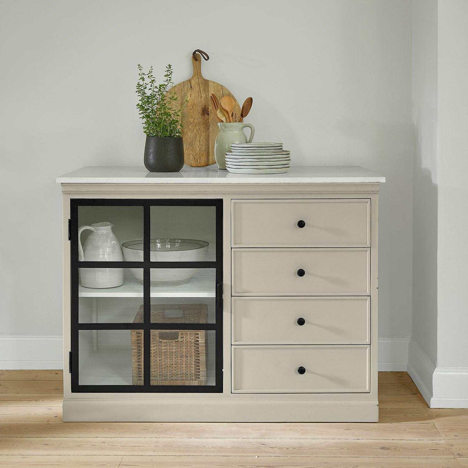 Mobile da cucina Orlévine Credenza beige con maniglie nere e porta in vetro, decorata con tagliere in legno e pianta verde