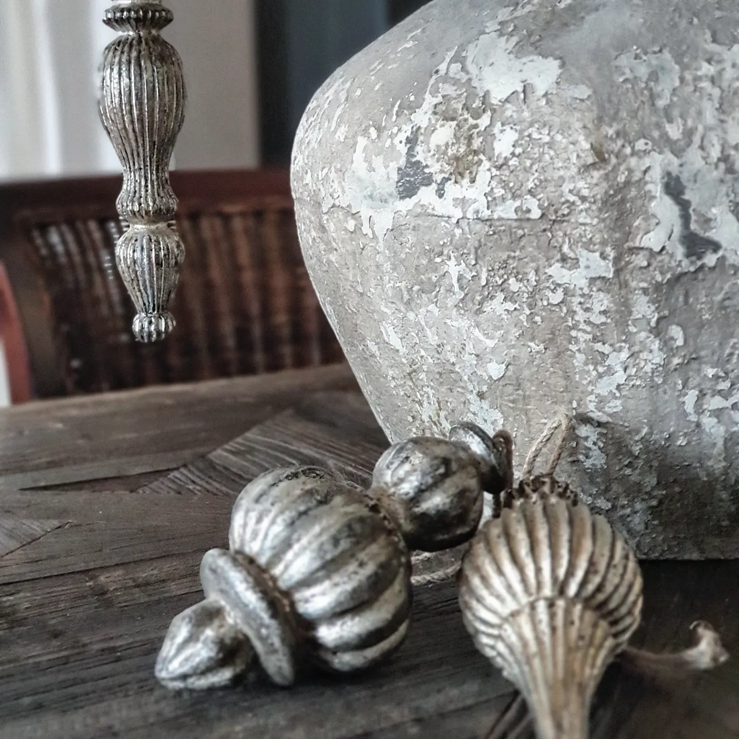 Decorazioni metalliche argentate su tavolo in legno accanto a vaso in ceramica invecchiata
