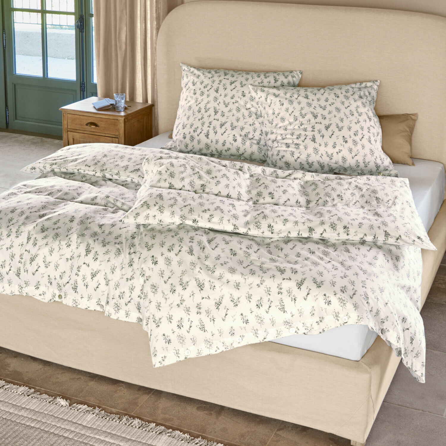 Biancheria da letto Somerlyn Biancheria da letto in cotone crema con delicata fantasia vegetale verde su letto con testiera beige
