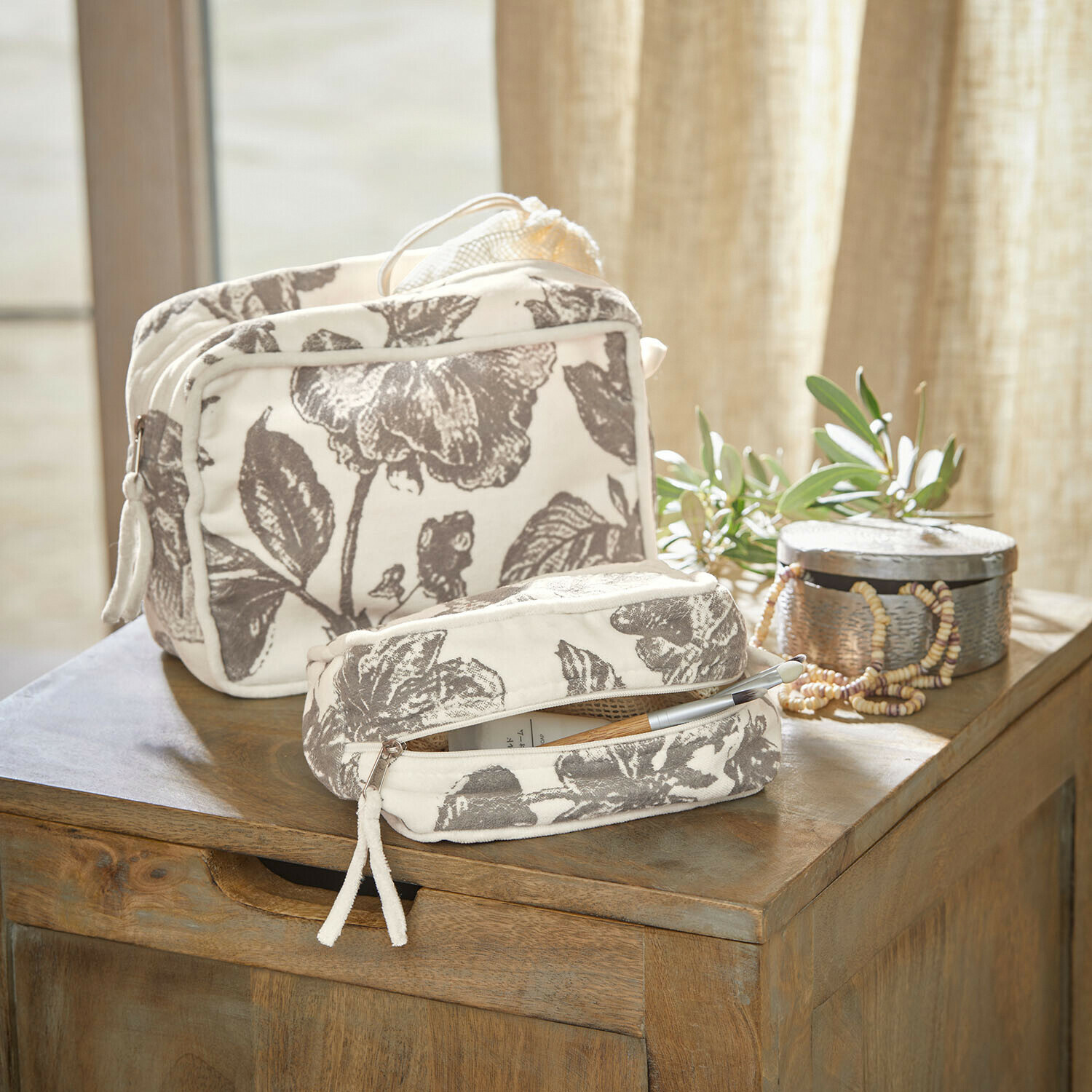 Coppia di pochette Brilonne Set di due trousse in cotone crema con motivo floreale grigio su tavolo in legno