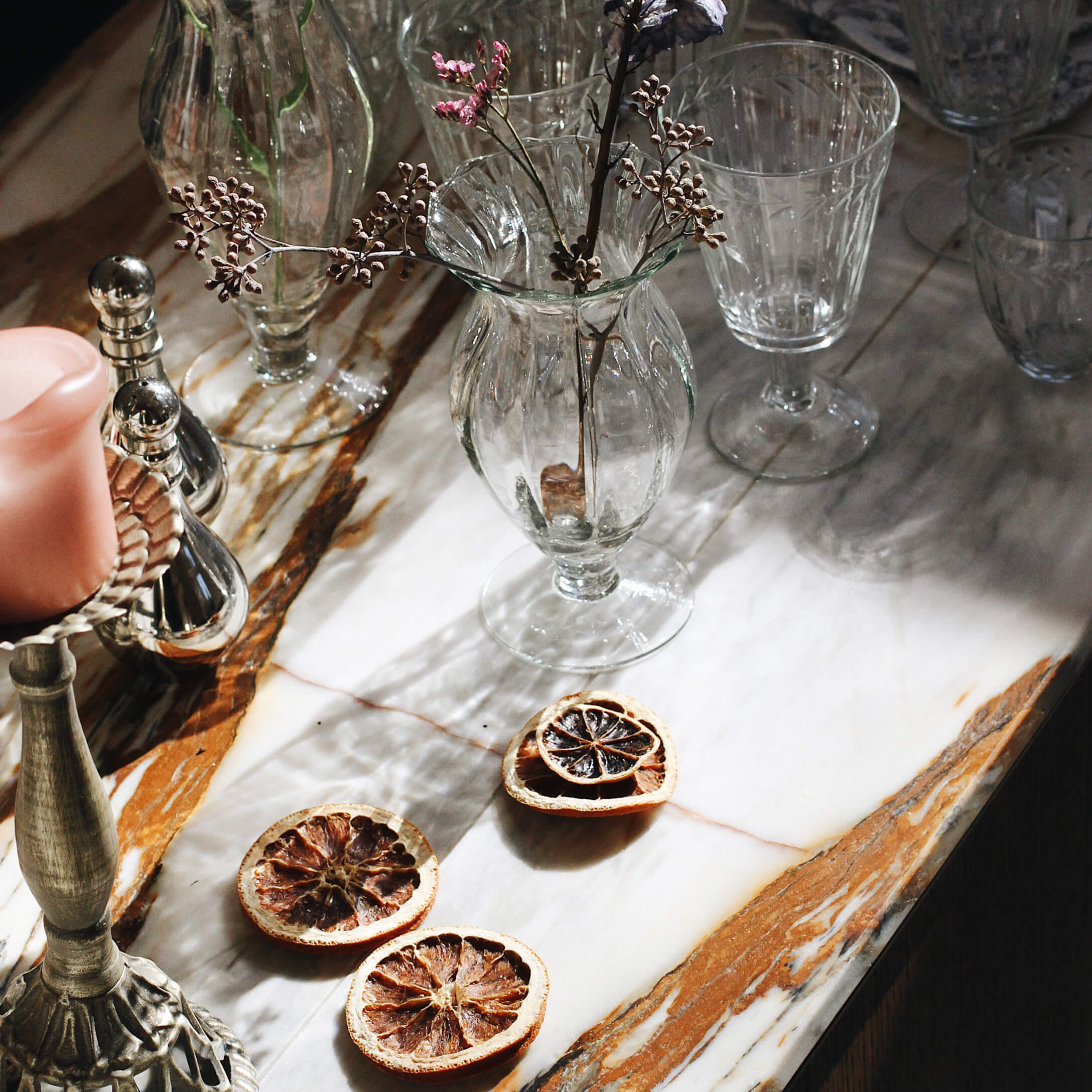 Vaso di vetro con fiori secchi su piano in marmo con fette decorative di frutta secca