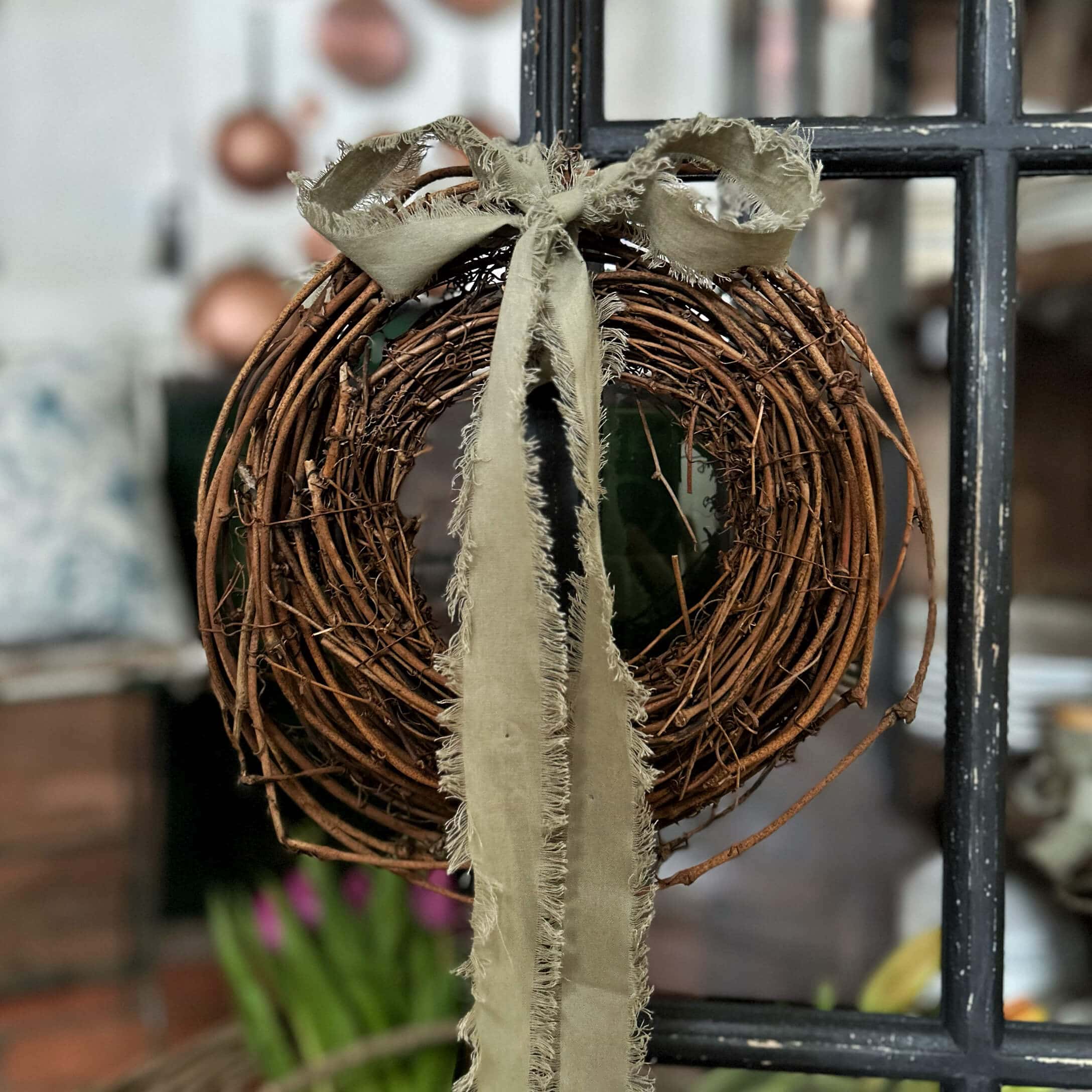 Corona decorativa in rami naturali con nastro beige sfrangiato per decorazione d'interni