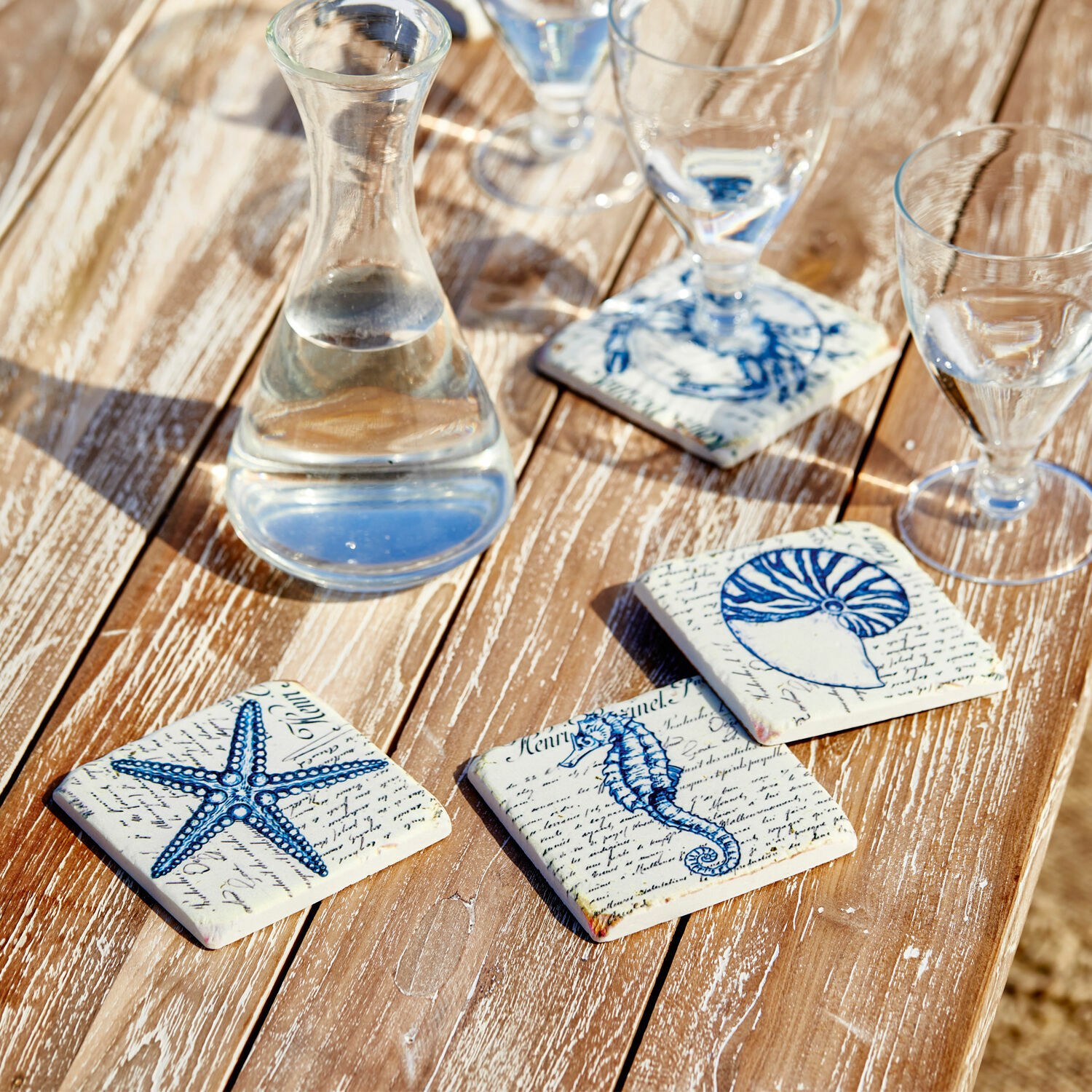 Set di 4 sottobicchieri Faune Marine Sottobicchieri in ceramica con motivi marini blu su tavolo in legno, decorazione elegante
