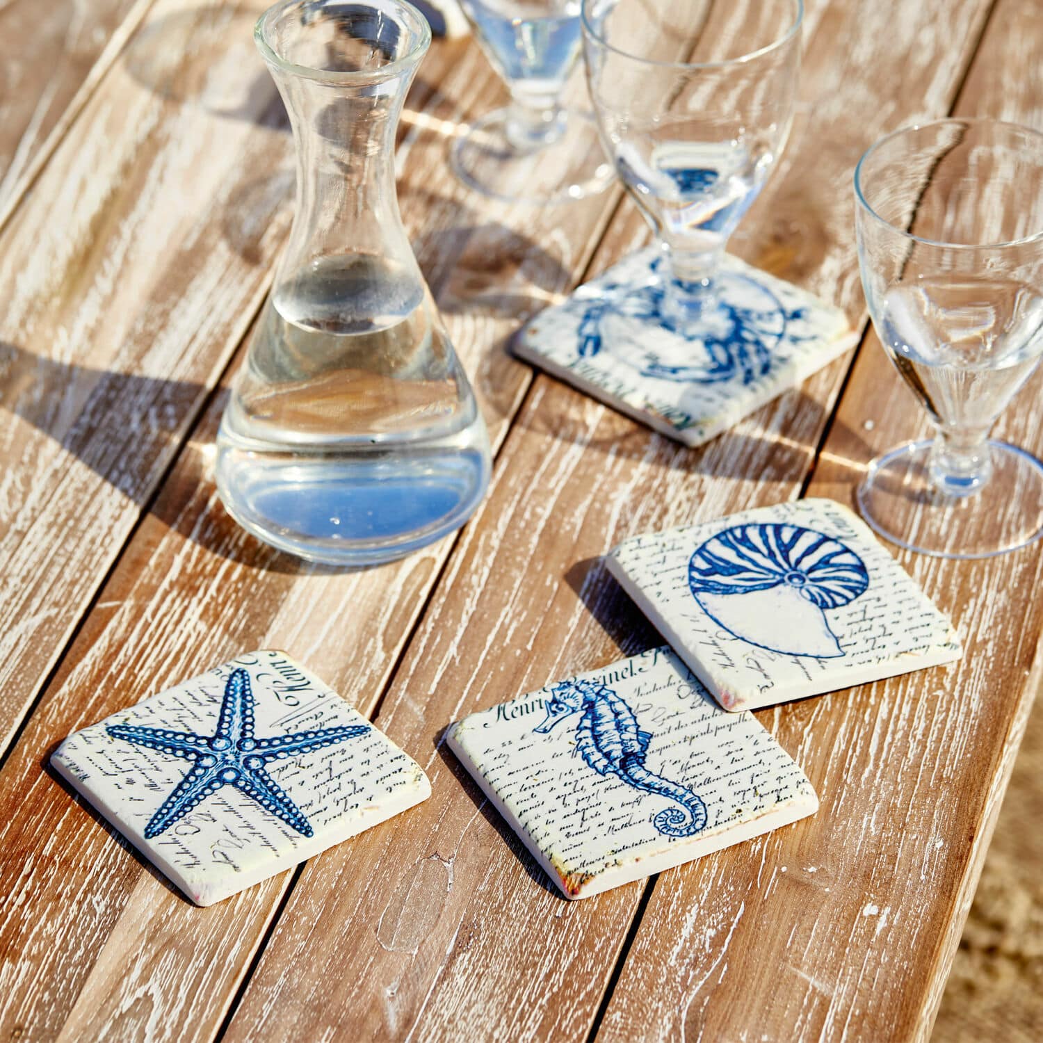 Set di 4 sottobicchieri Faune Marine Sottobicchieri in ceramica con motivi marini blu su tavolo in legno, decorazione elegante