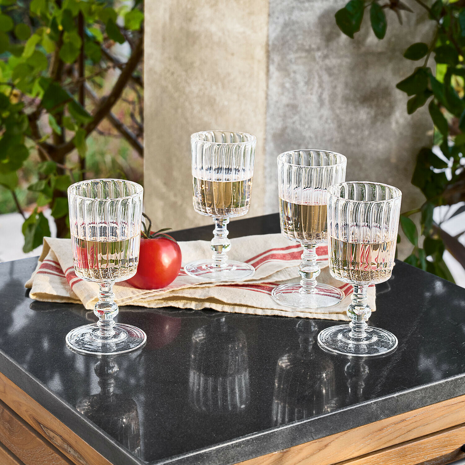 Set di 4 bicchieri Lianzo Quattro bicchieri trasparenti in vetro scanalato con bevanda chiara su tavolo nero lucido