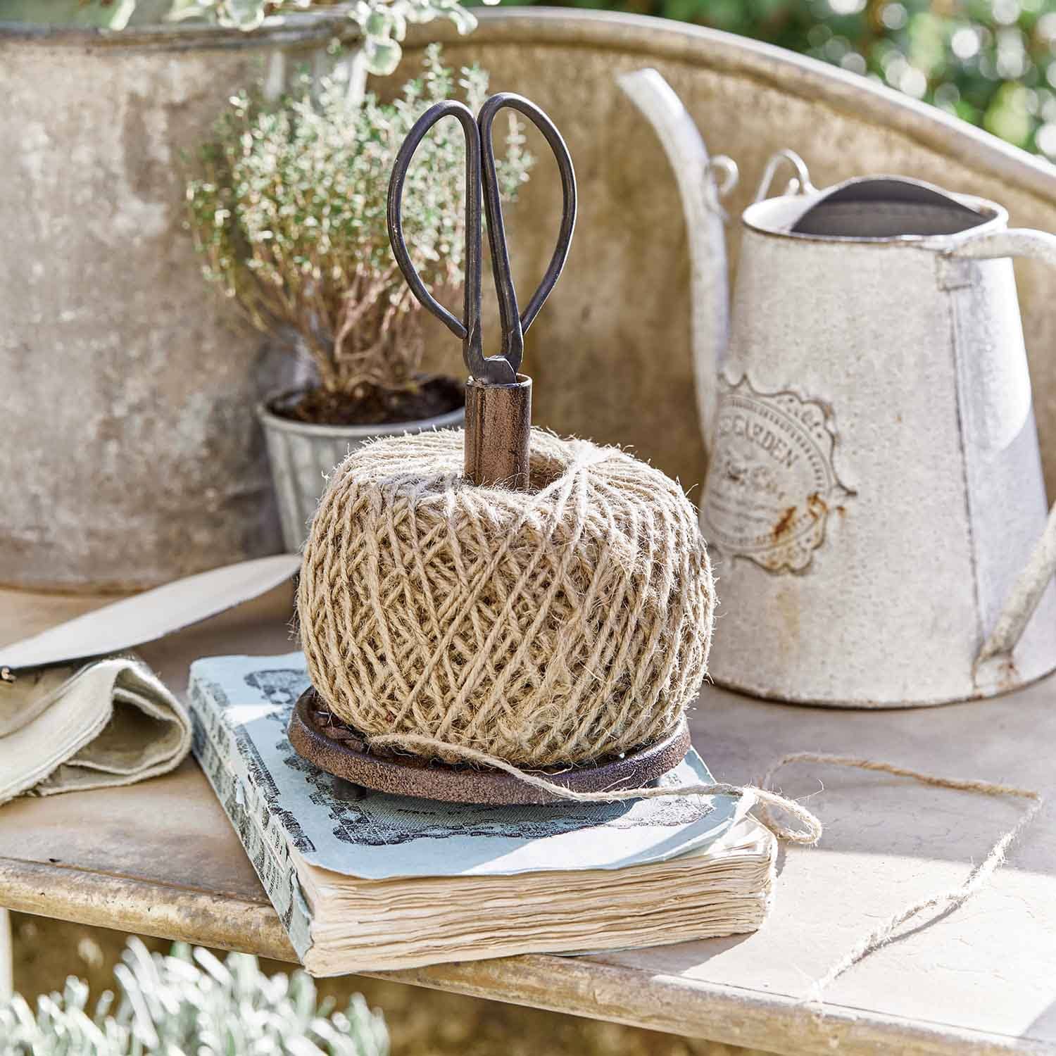 Spola di spago di juta naturale su supporto metallico con forbici in ambiente rustico da giardino