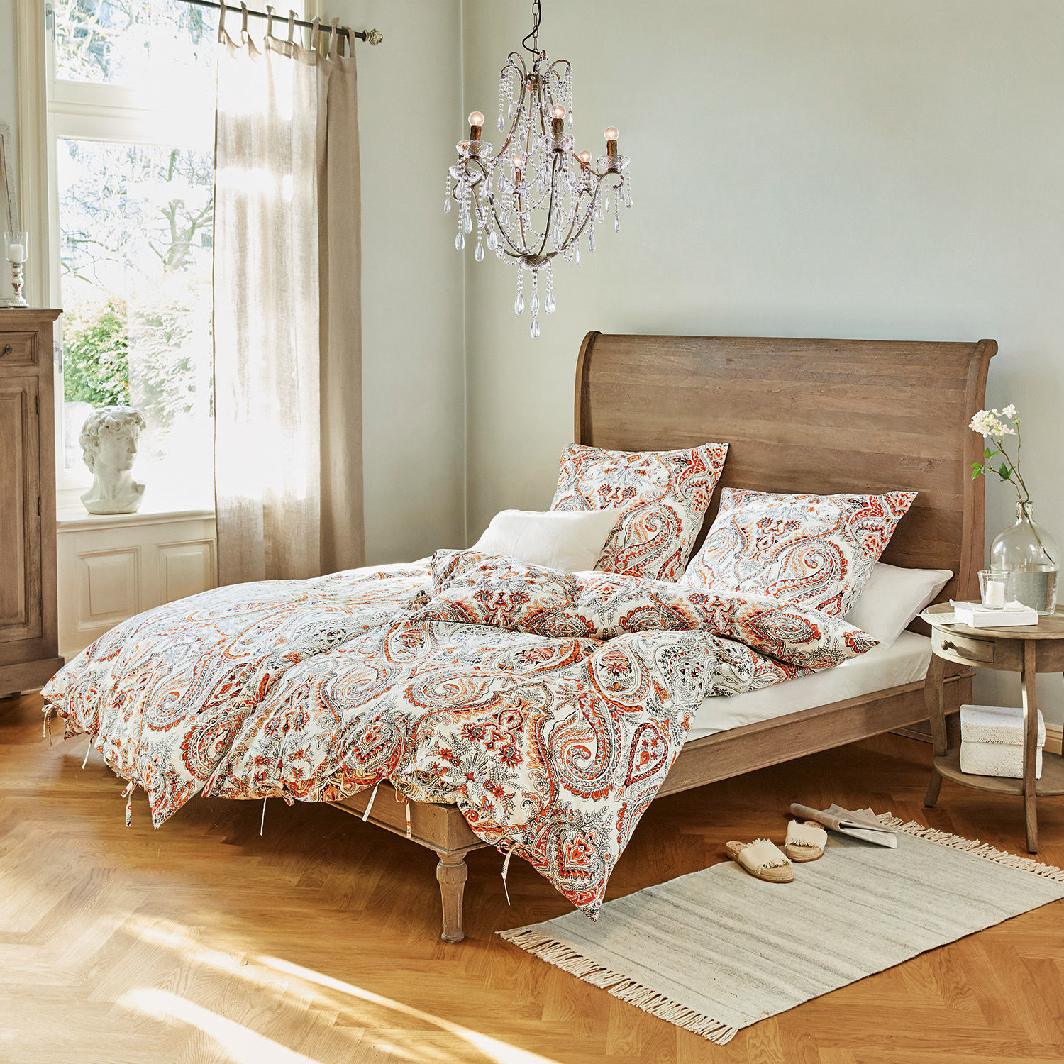 Letto Saint-Germier Camera da letto con letto in legno e biancheria da letto con motivo paisley rosso e bianco, tappeto e lampadario di cristallo