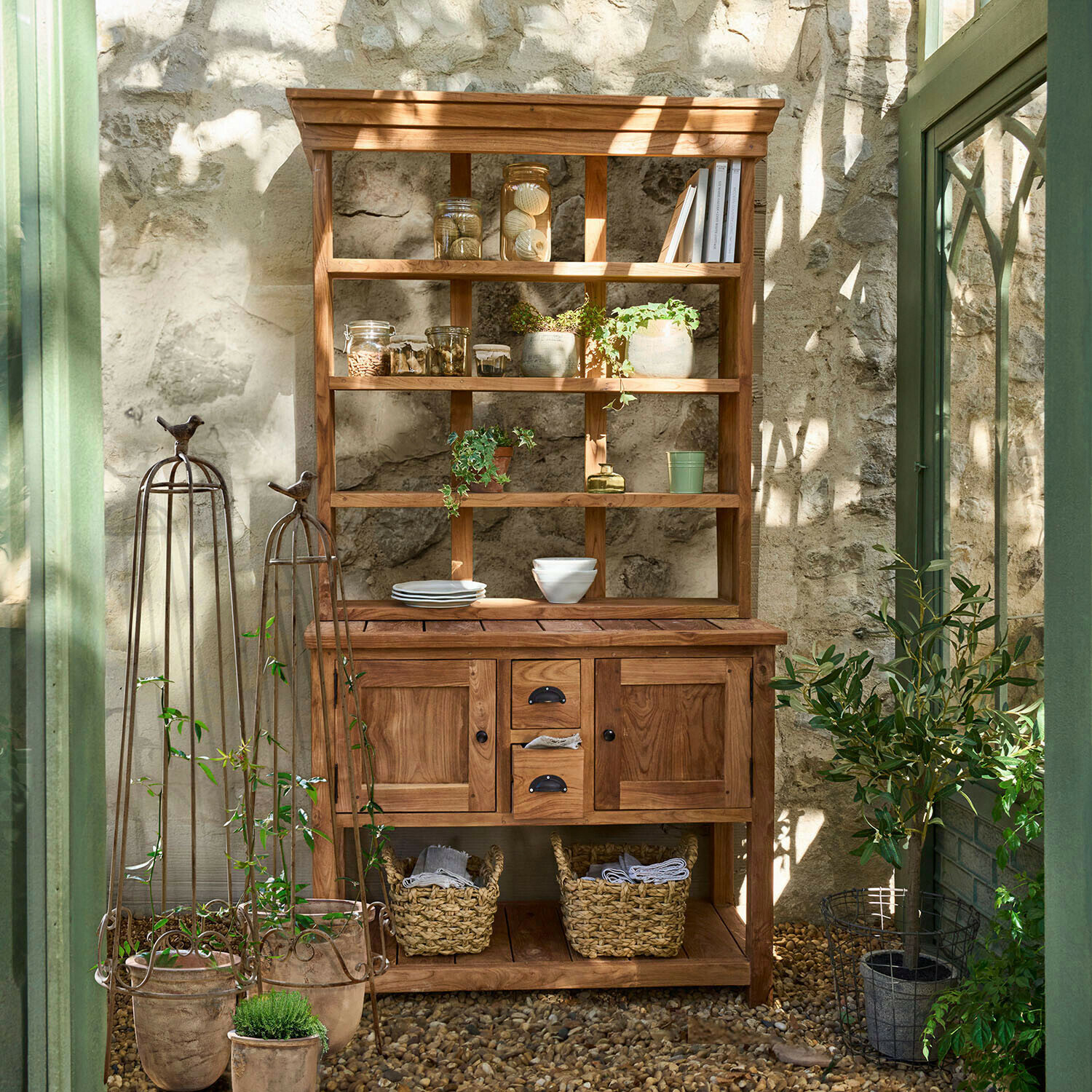 Credenza Ellamie Credenza in legno naturale con scaffali e cassetti, decorata con piante e stoviglie in ambiente luminoso