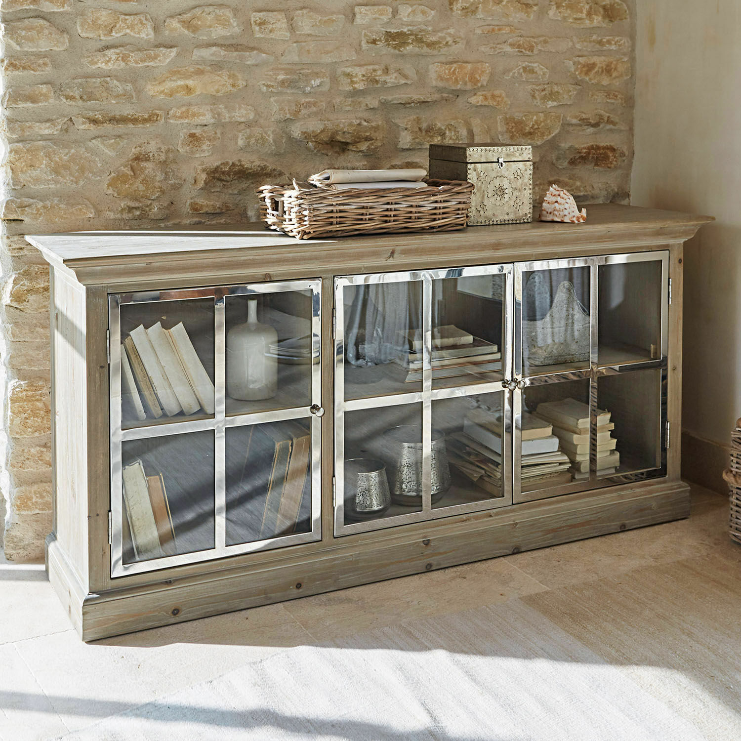 Credenza bassa Keyport Credenza in legno chiaro a tre ante con vetri, libri e decorazioni in ambiente rustico