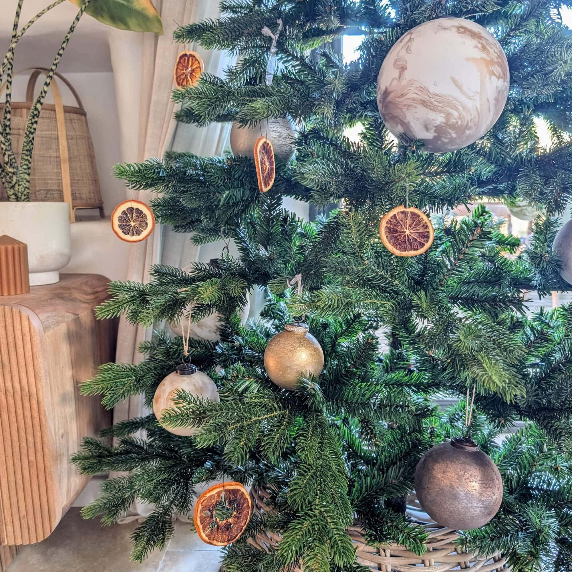 Albero di Natale verde decorato con fette di arancia essiccate e palline dorate e beige