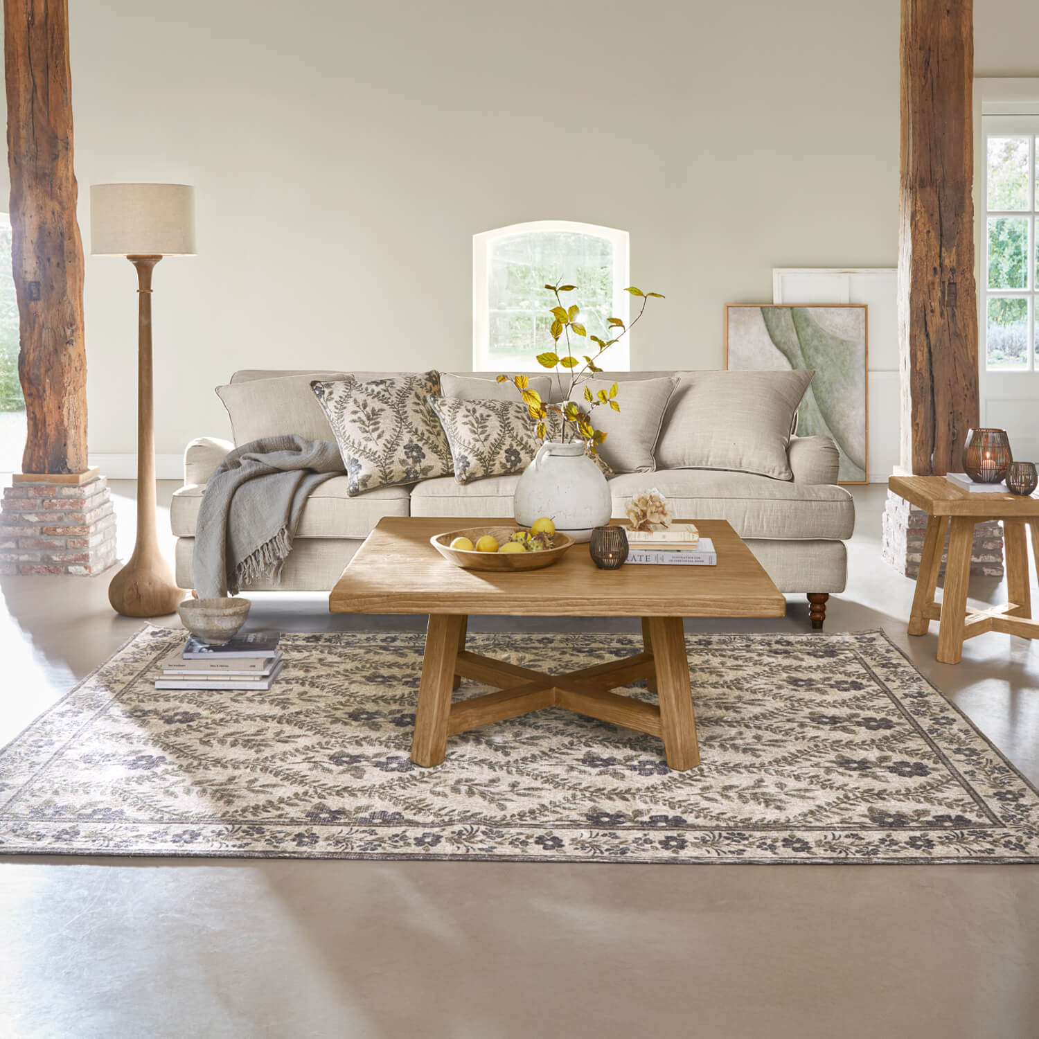 Soggiorno accogliente con divano beige, tavolino in legno e tappeto con motivo floreale