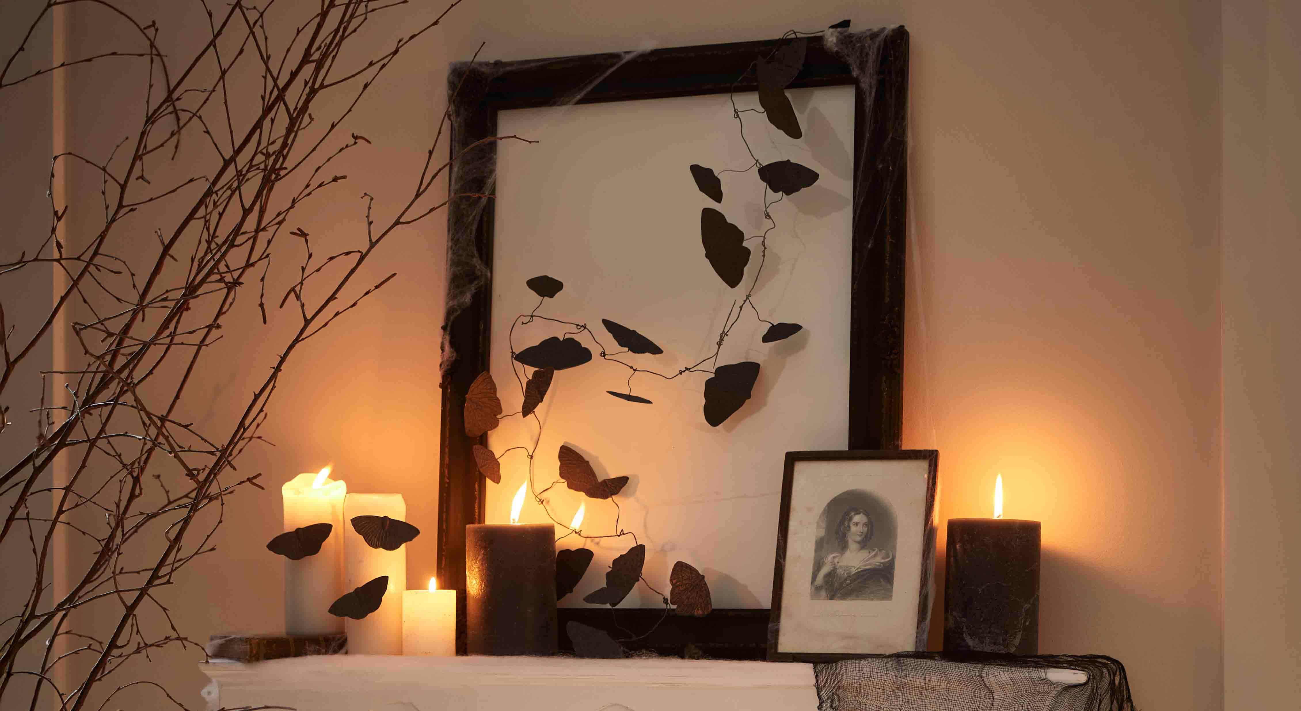 Candele nere e bianche con decorazioni di farfalle in filo su cornice, illuminazione d'atmosfera