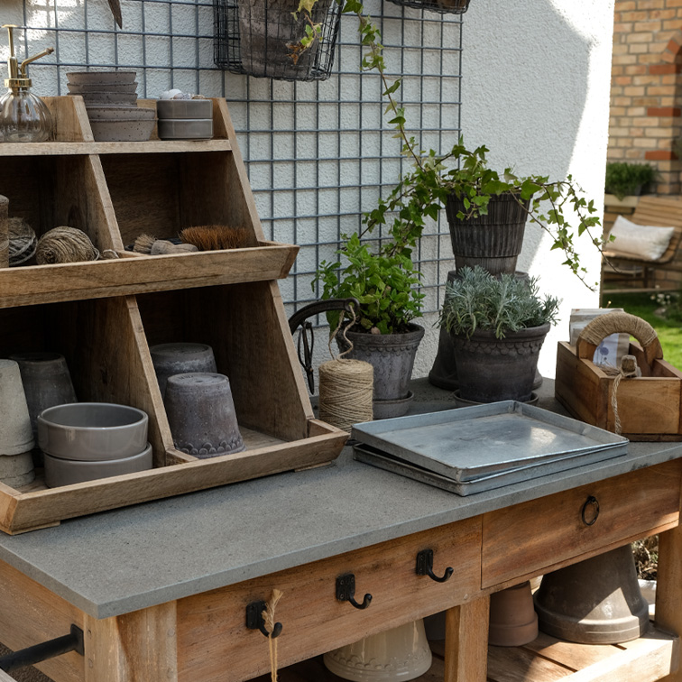 Tavolo da giardino in legno con attrezzi da piantagione e vasi in terracotta in colori naturali, decorazione esterna