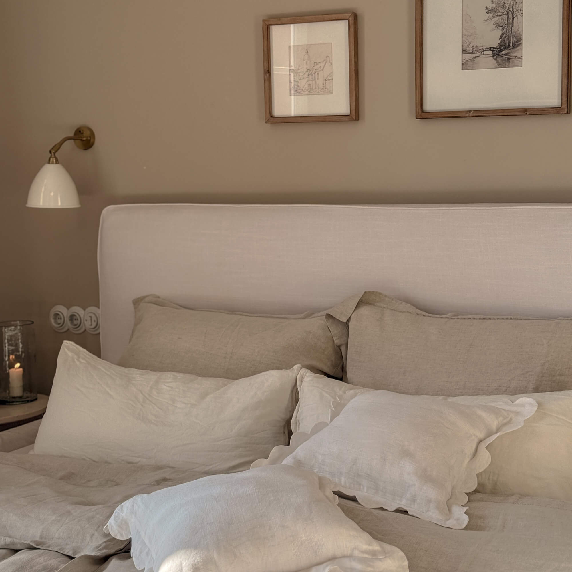 Camera accogliente con biancheria da letto beige in lino e testiera imbottita chiara