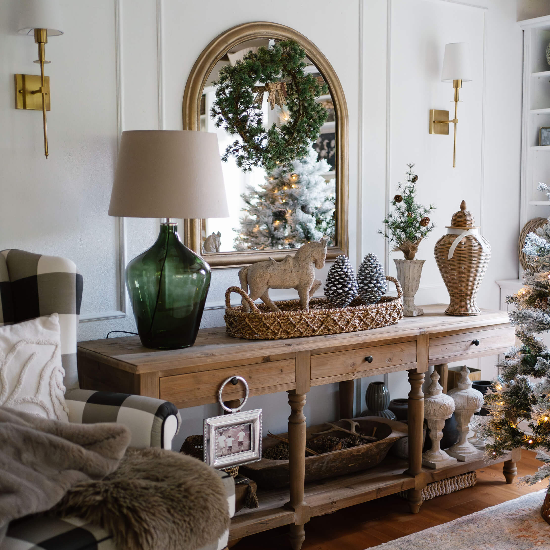 Tavolo in legno con decorazioni natalizie, lampada verde e specchio con corona in soggiorno accogliente