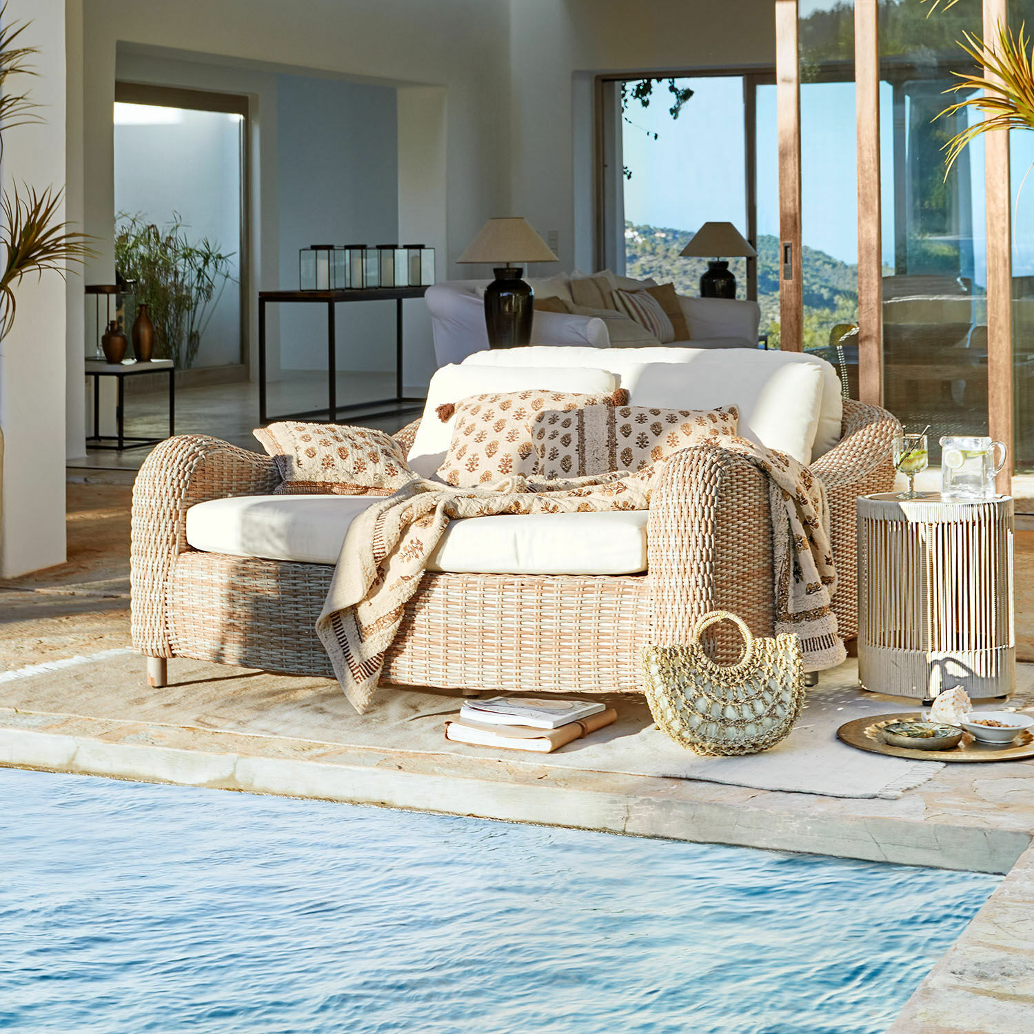 Divano lounge Heloite Divano in rattan naturale con cuscini crema e coperta vicino alla piscina in interno moderno