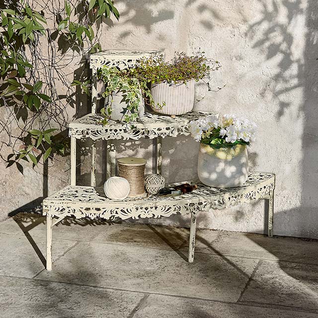 Scaletta in metallo crema con motivo traforato, decorata con vasi e piante, arredo da giardino