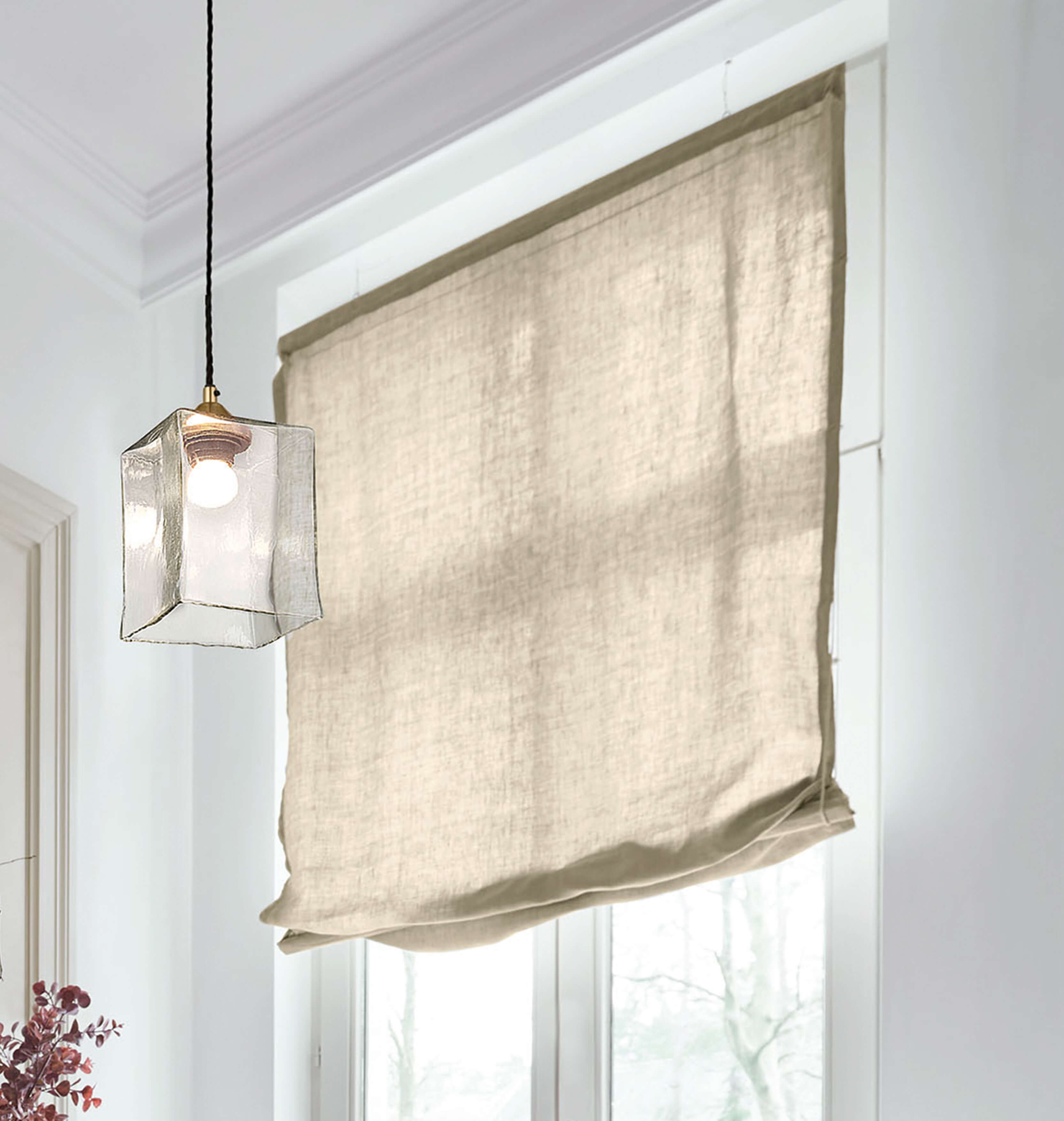Tenda a rullo beige in lino in ambiente luminoso con lampada a sospensione in vetro trasparente