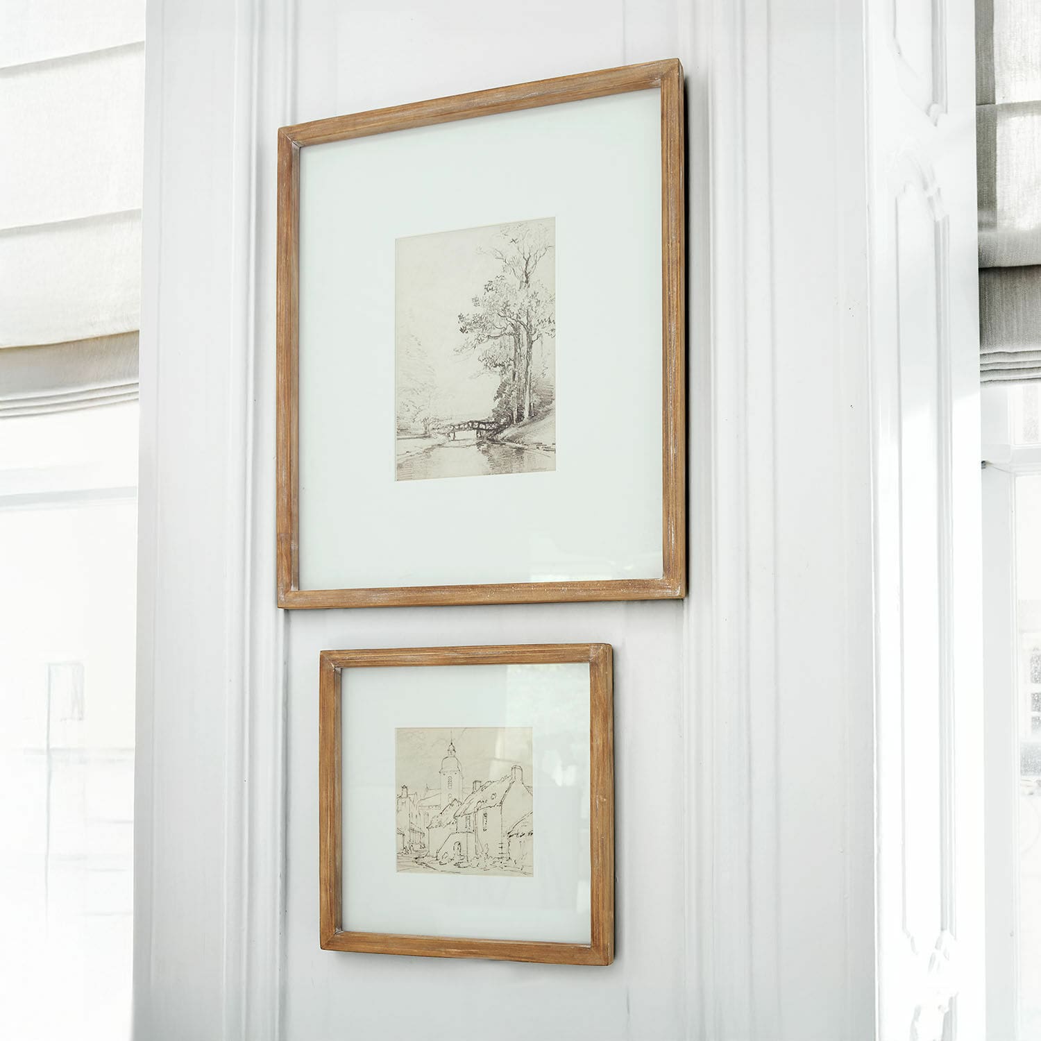 Coppia di quadri Juvarel Due cornici rustiche in legno con disegni di paesaggi appese a parete bianca luminosa