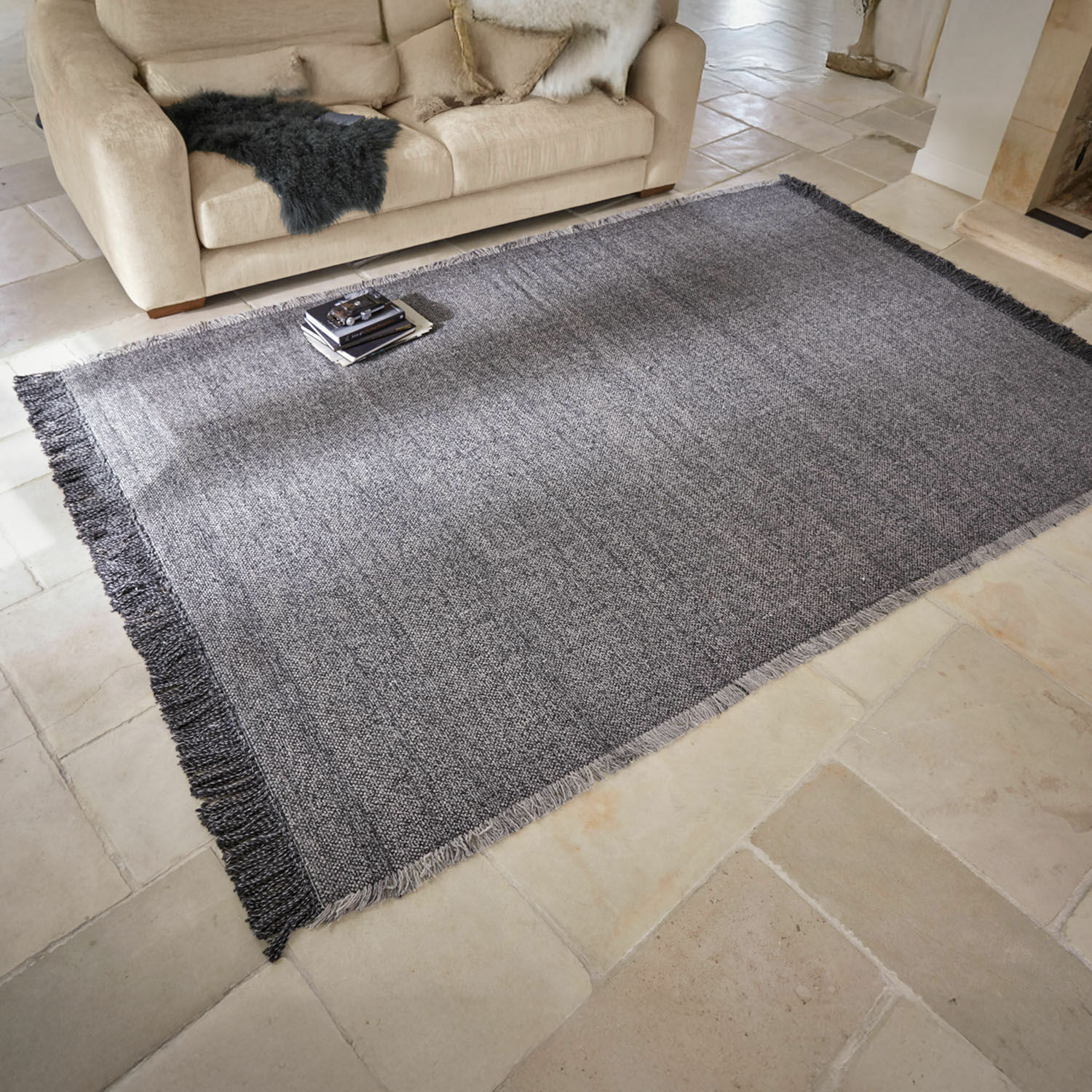Tappeto per interni ed esterni Marivela Tappeto grigio con frange su pavimento chiaro in soggiorno con divano beige e cuscini