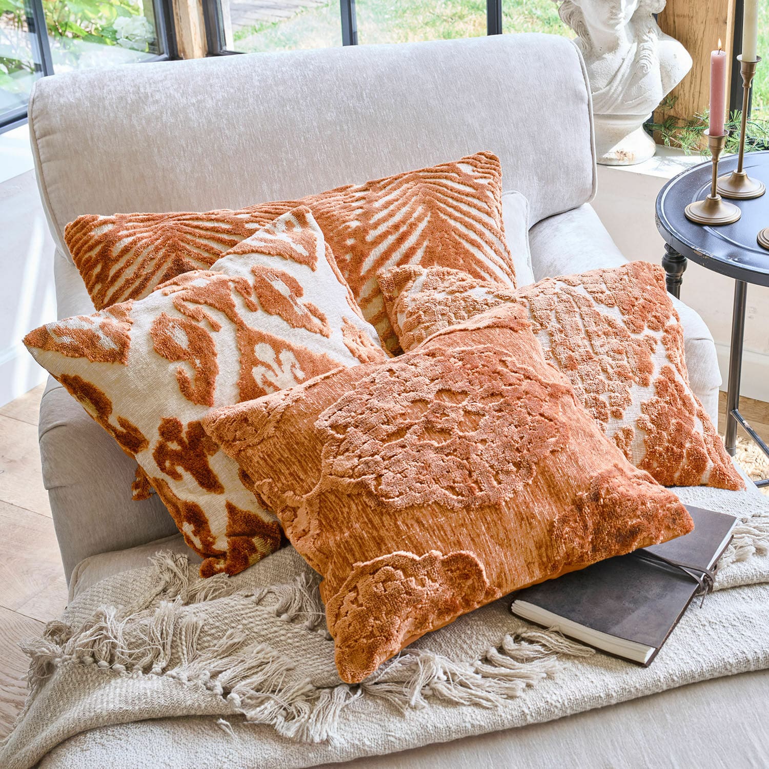 Set di 4 copricuscini Samirad Set di cuscini decorativi arancioni con motivi su divano chiaro con coperta a frange