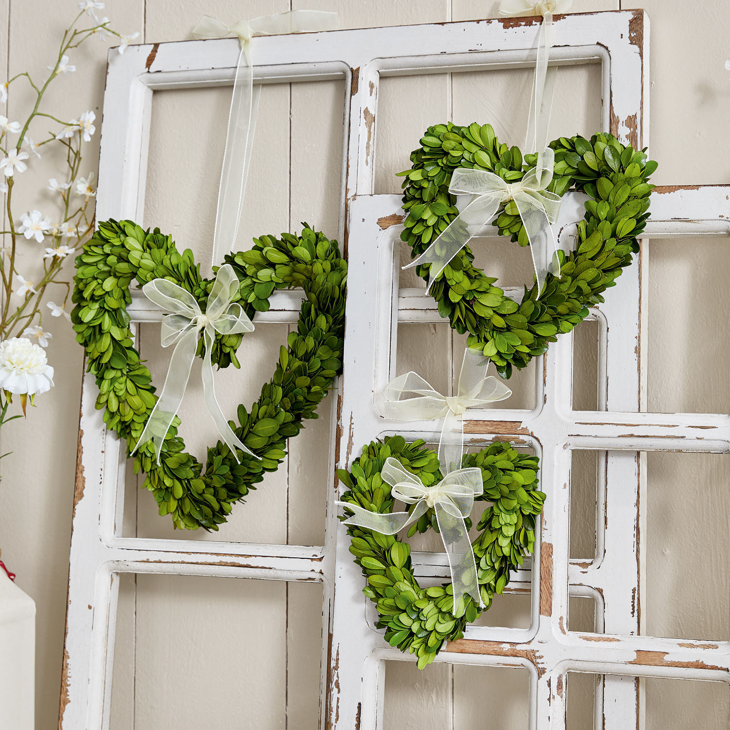 Set di 3 decorazioni da appendere Venia Cuori verdi di foglie con fiocchi bianchi appesi a una cornice bianca decorativa in stile shabby