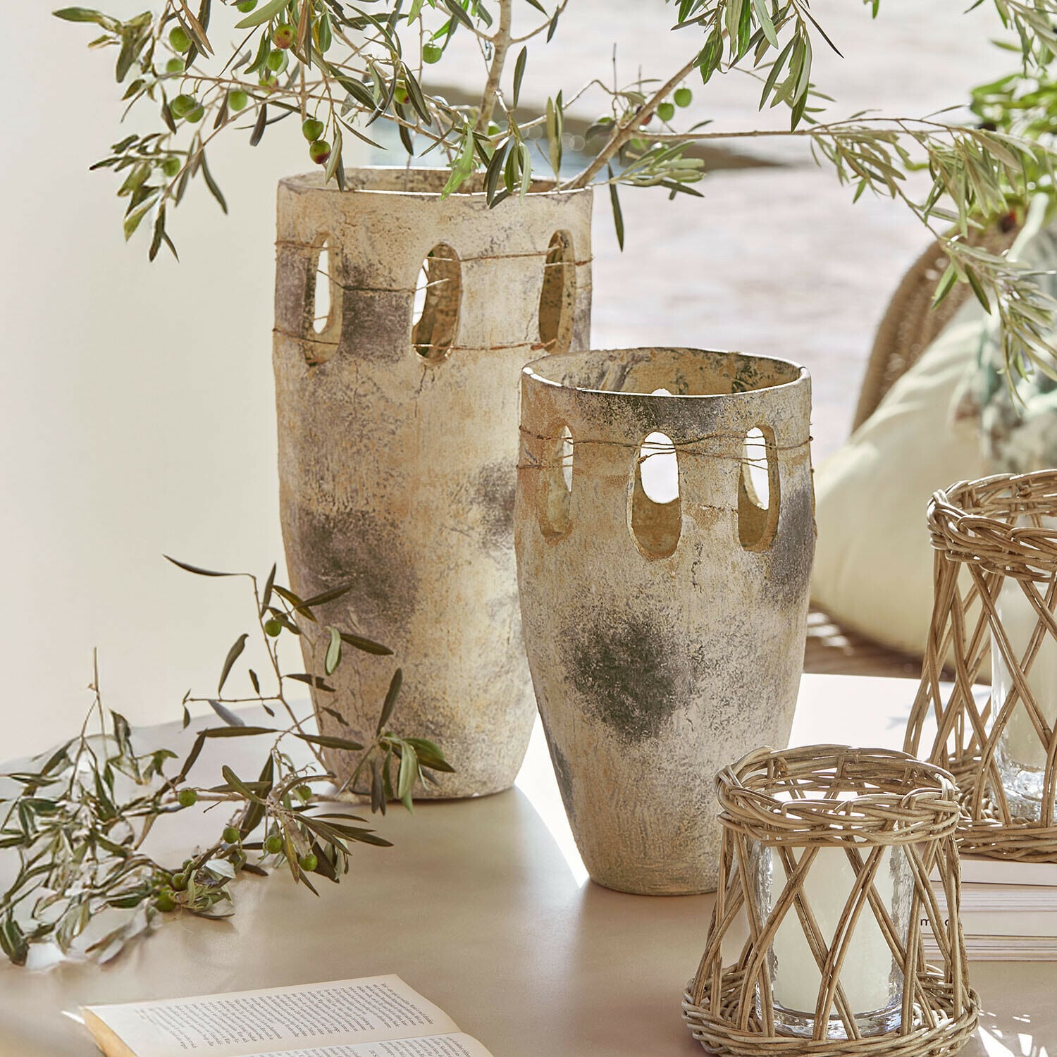 Coppia di vasi Delunas Due vasi decorativi in pietra beige-grigio con aperture e rami di ulivo su un tavolo