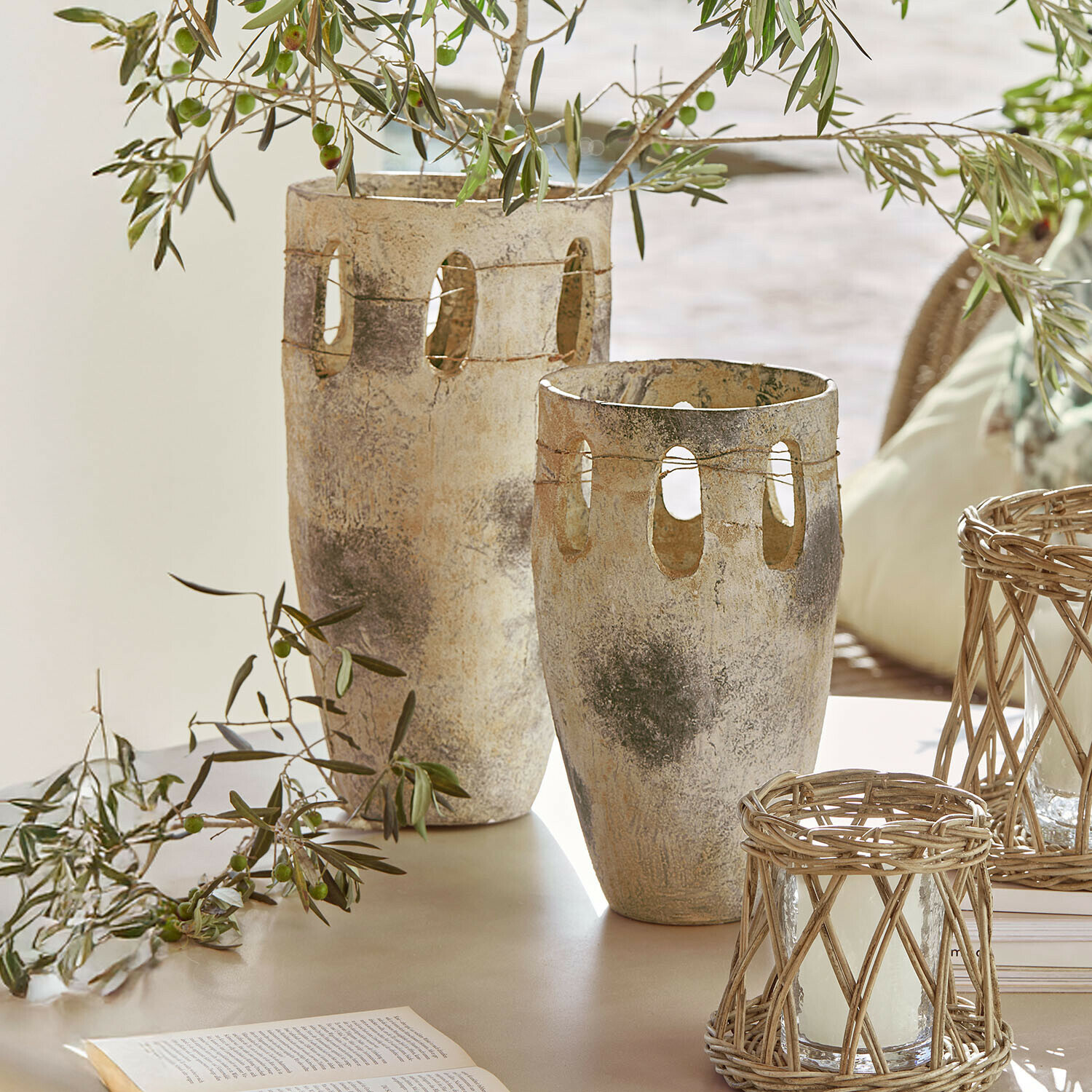 Coppia di vasi Delunas Due vasi decorativi in pietra beige-grigio con aperture e rami di ulivo su un tavolo