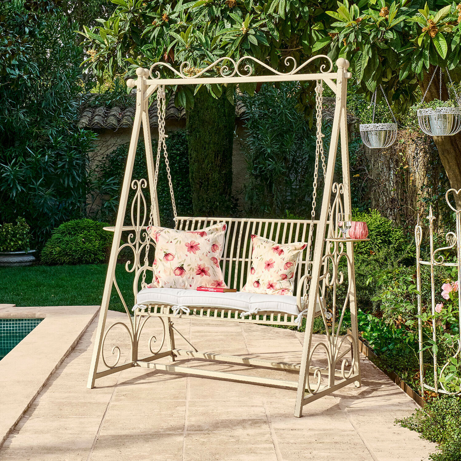 L"altalena di Hollywood Iveralia Dondolo da giardino in metallo crema con cuscini floreali su terrazza vicino piscina