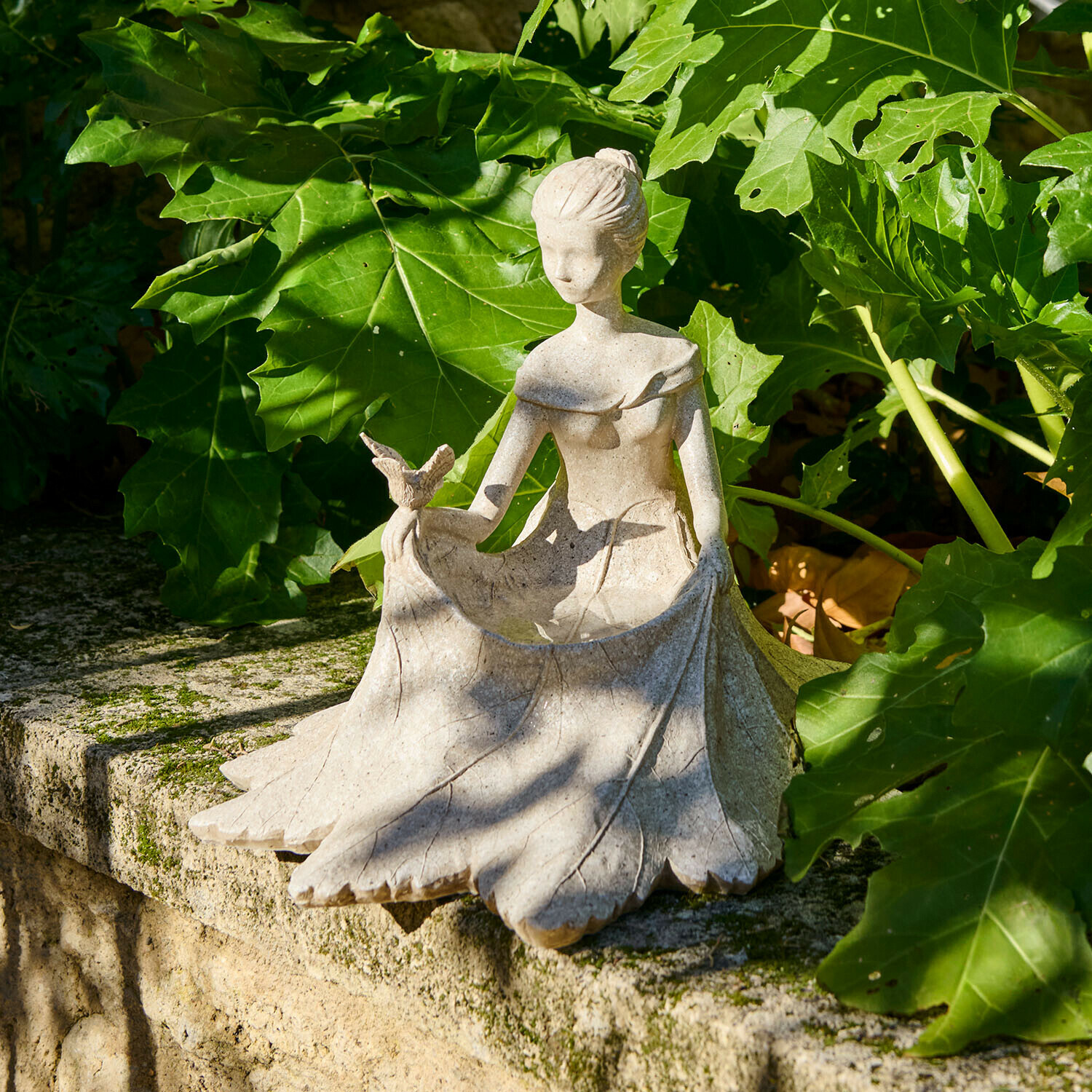 Figura decorativa Finnedra Statua in pietra di donna con uccello, decorazione da giardino su muretto in pietra tra foglie verdi